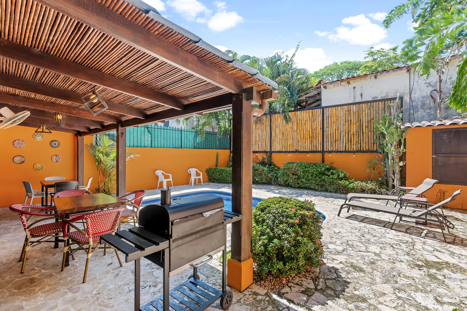 An outdoor patio with a covered seating area and a grill.