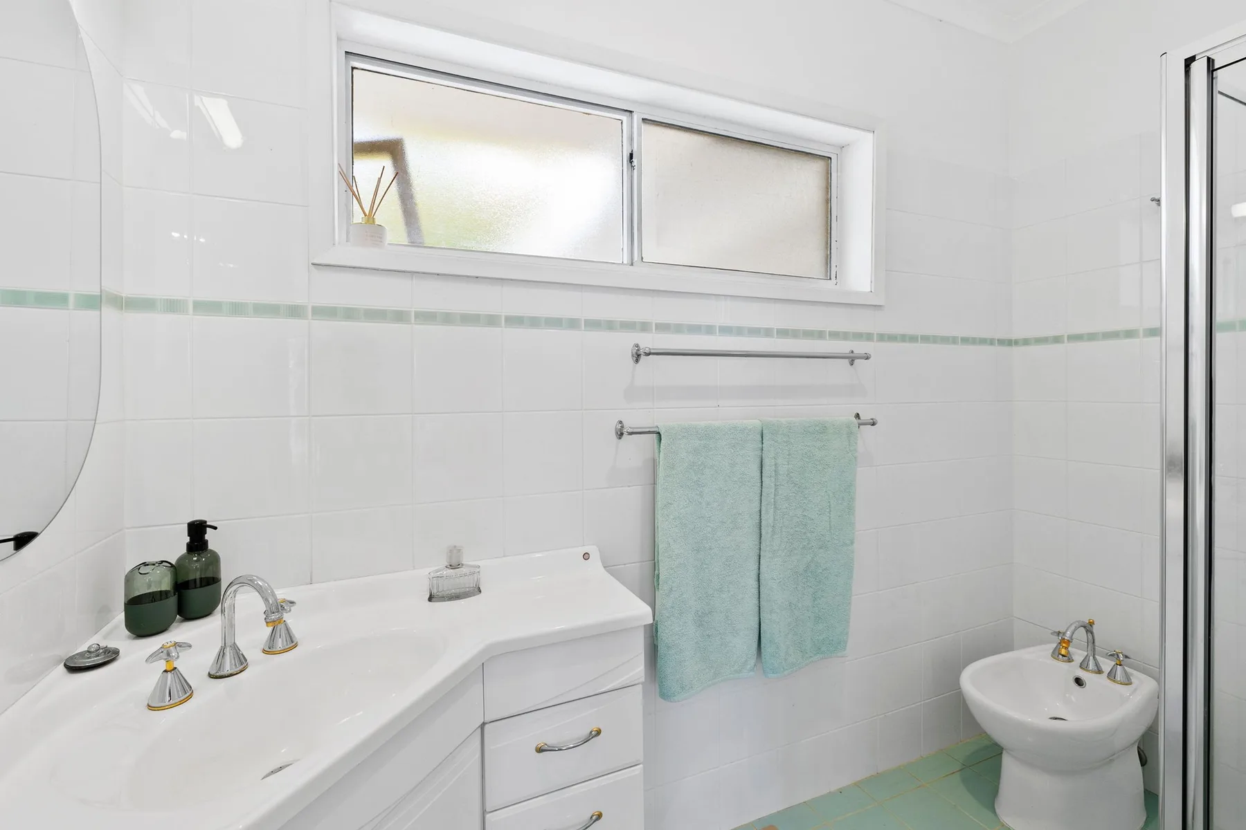 Un baño luminoso con azulejos, lavabo, toallas y bidé.