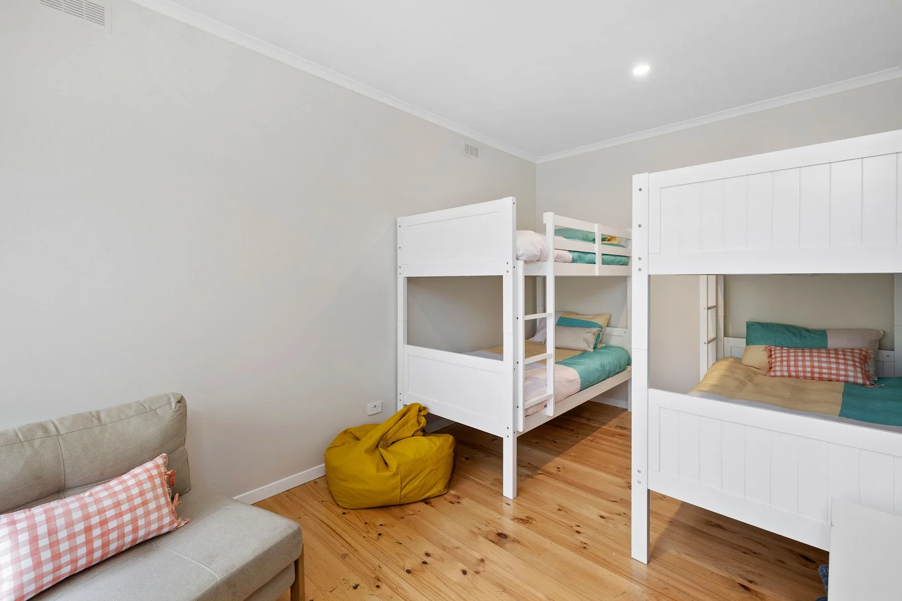 Un dormitorio con literas, un puf y una pequeña zona de estar.