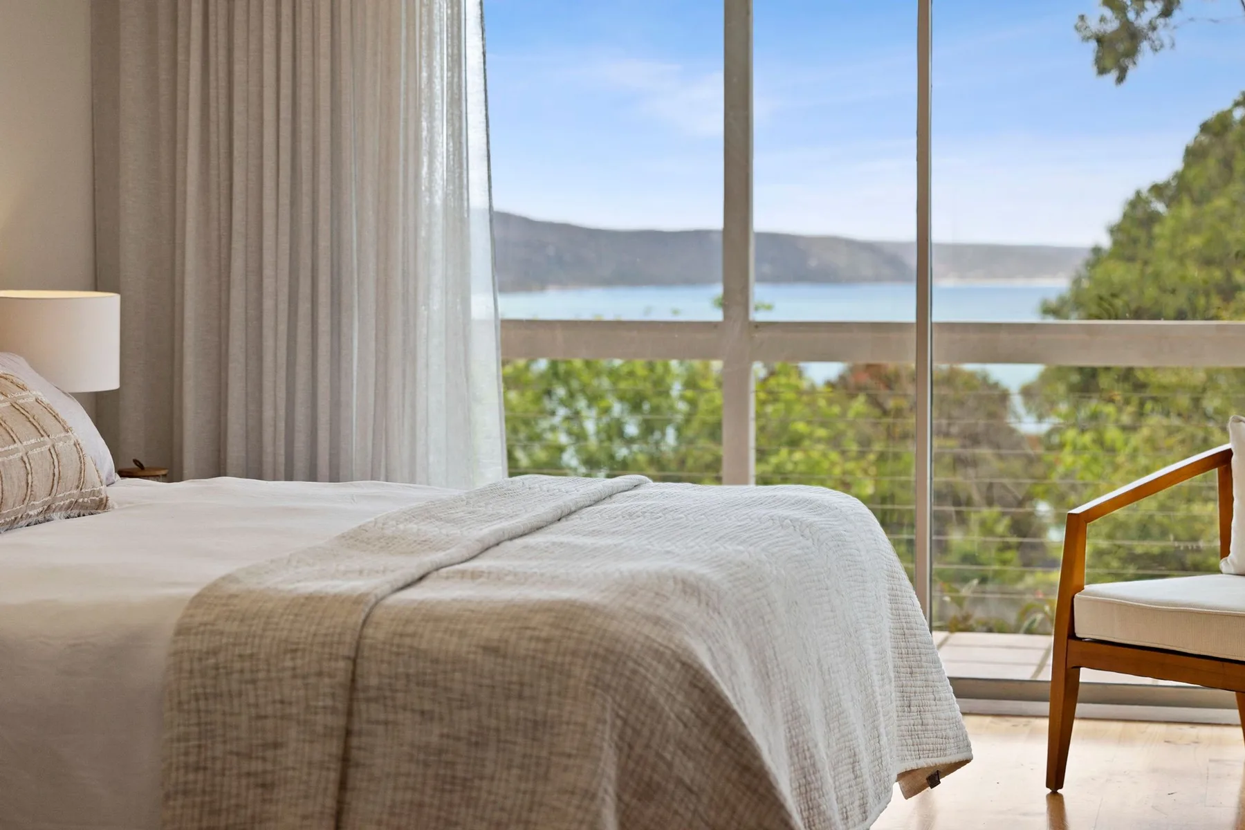 Un dormitorio con una cama junto a una gran ventana con vistas a un lago.