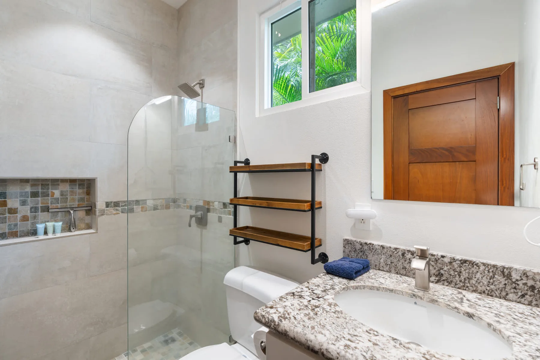 Un baño luminoso con ducha de vidrio, lavabo y puerta de madera.