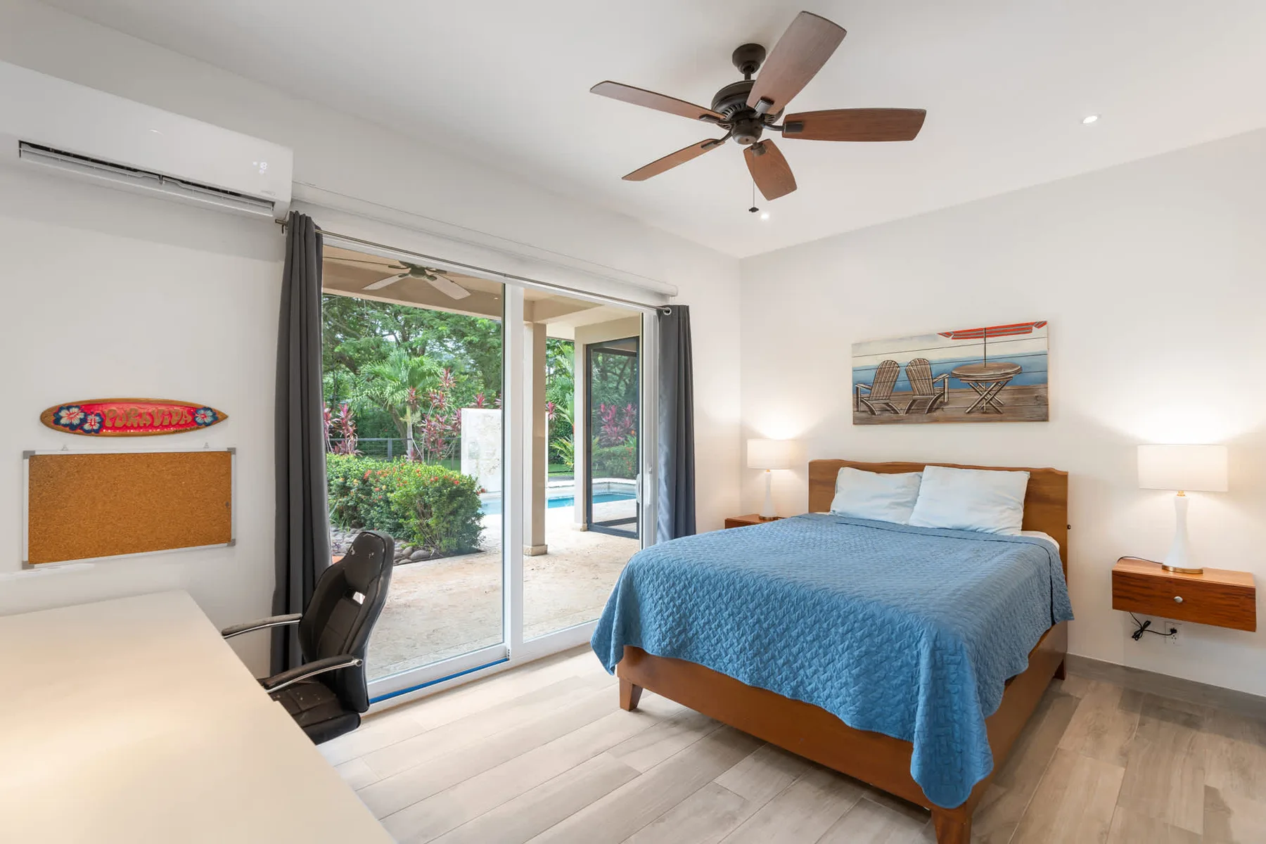 A bedroom with a bed beside sliding glass doors opening onto a garden.