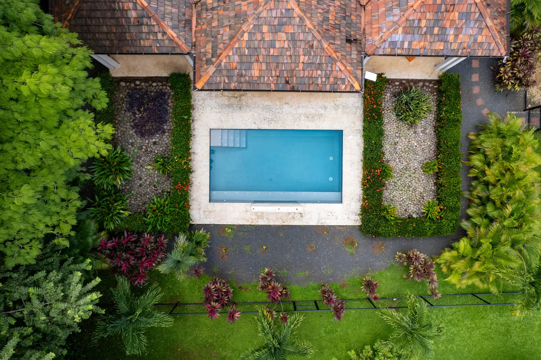 Una vista aérea muestra una piscina rectangular rodeada de caminos pavimentados y vegetación.