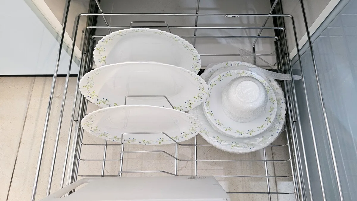 Un escurridor sostiene platos blancos y un cuenco poco profundo con borde floral.