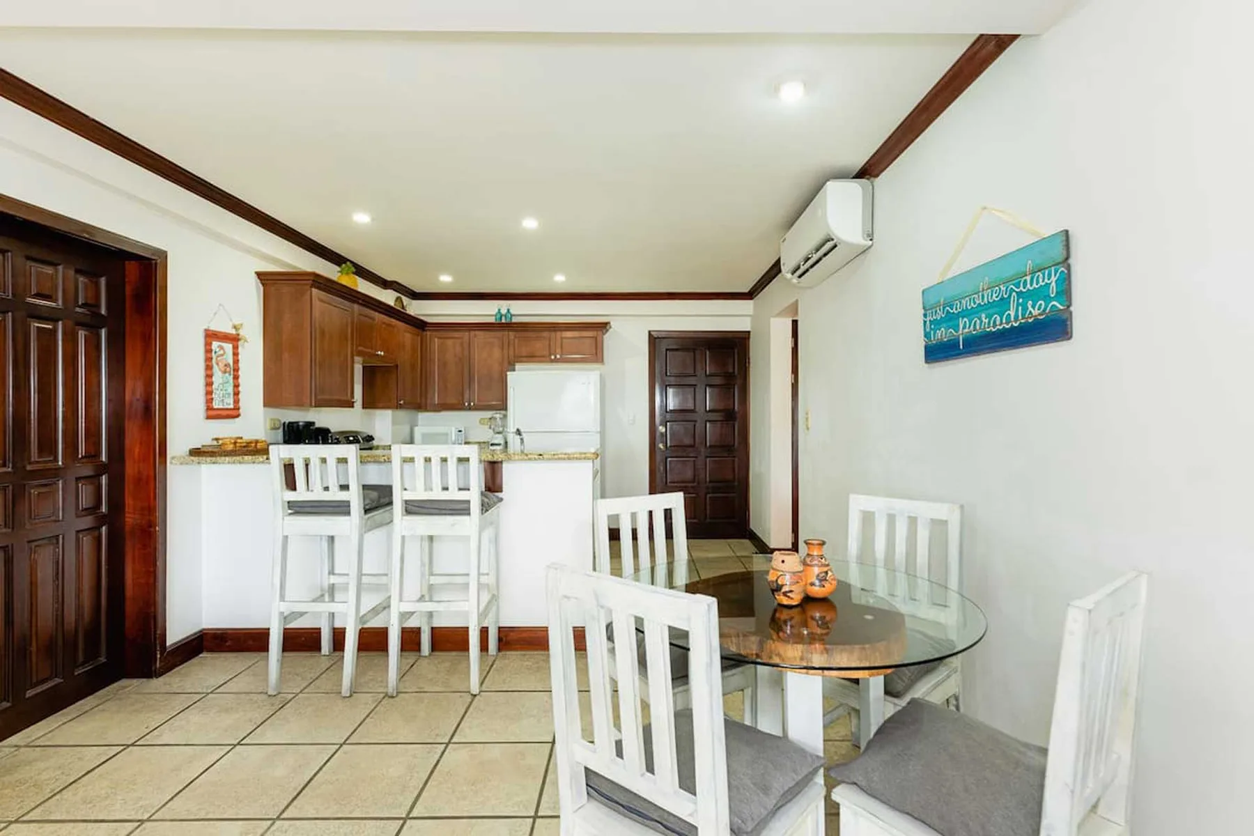 A dining area with a glass table and chairs beside a compact kitchen.