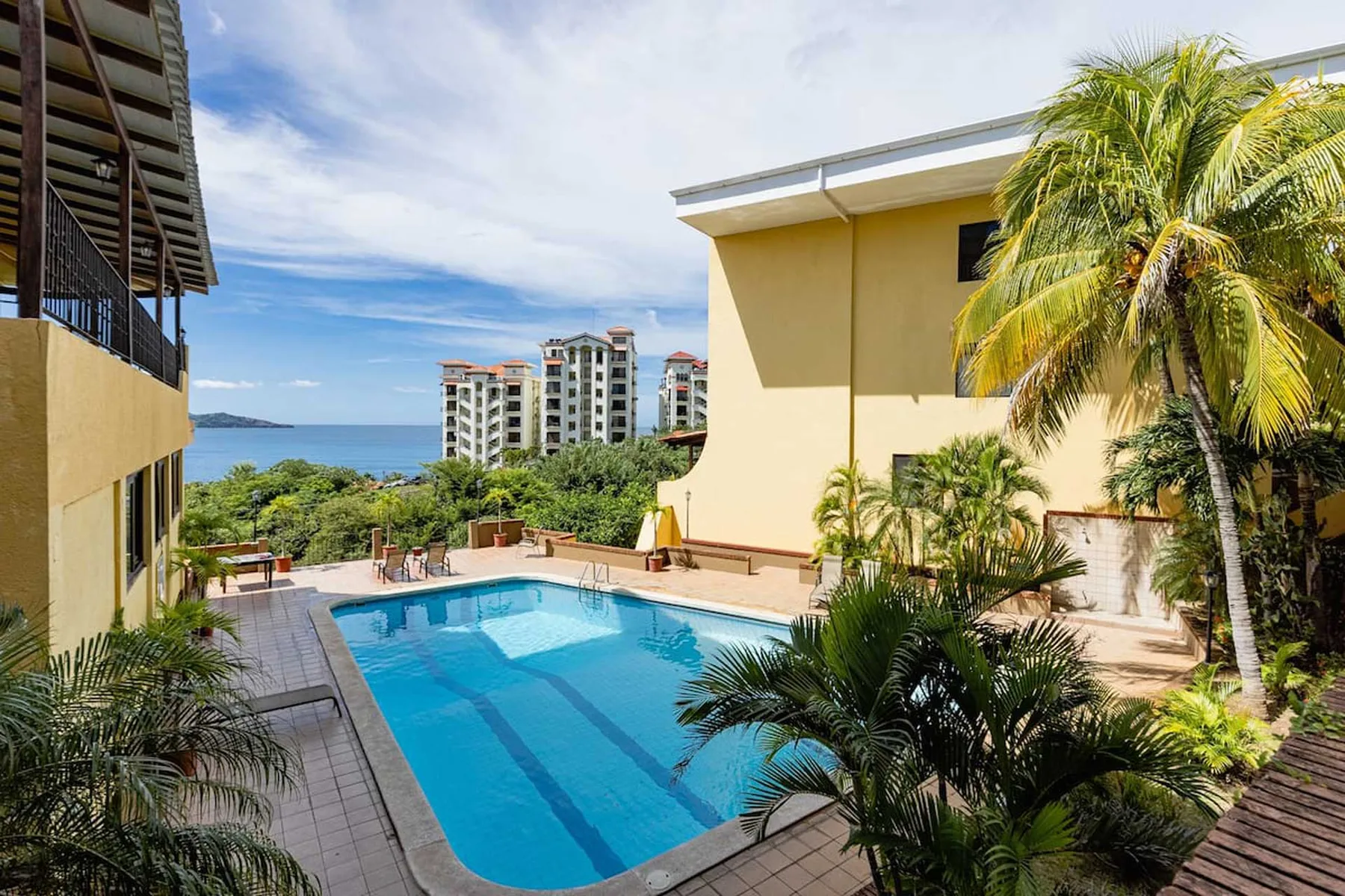 Shared amenity: An outdoor swimming pool surrounded by palm trees and nearby buildings.