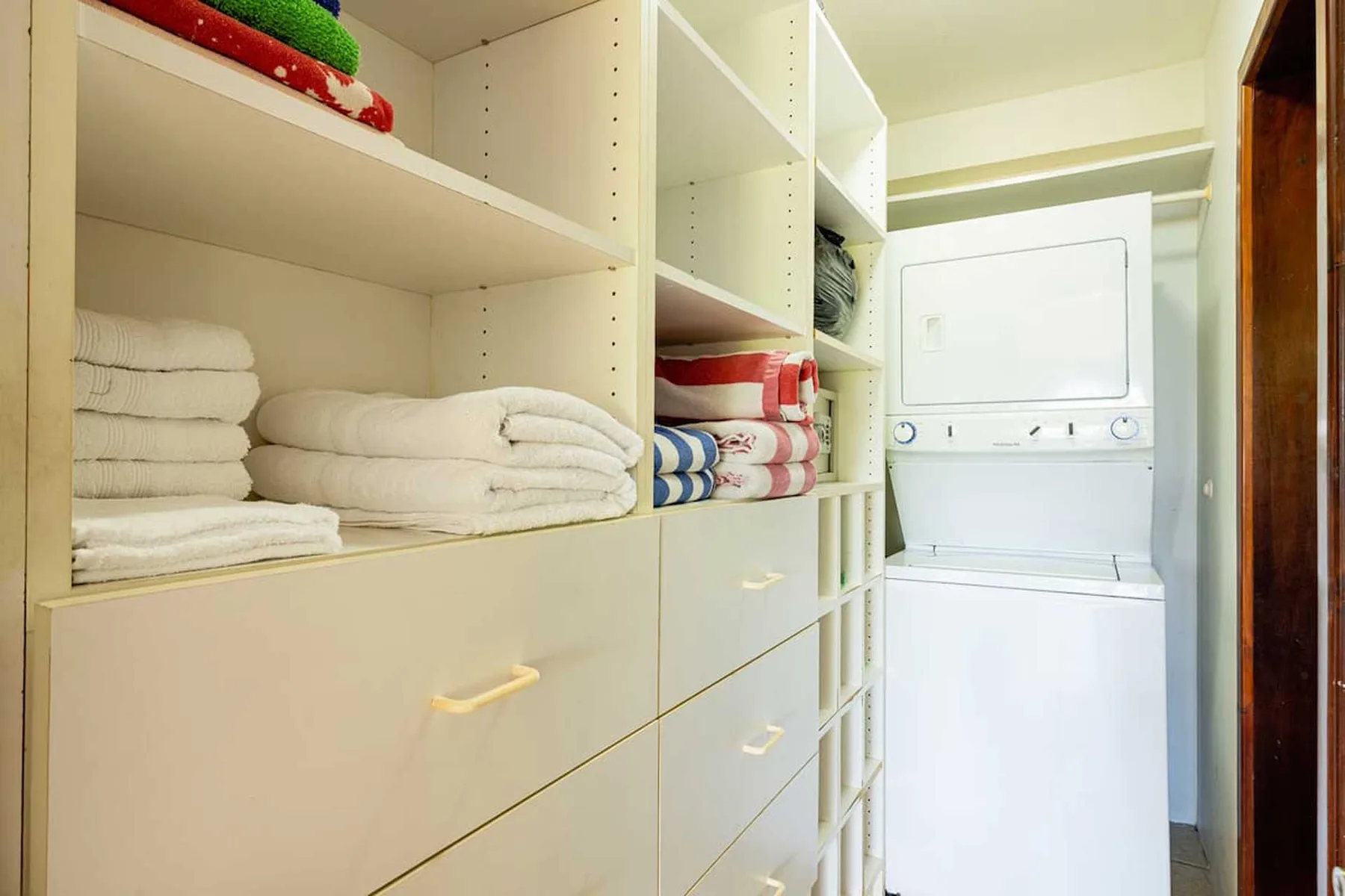 A laundry room with a washer and shelves of folded towels.