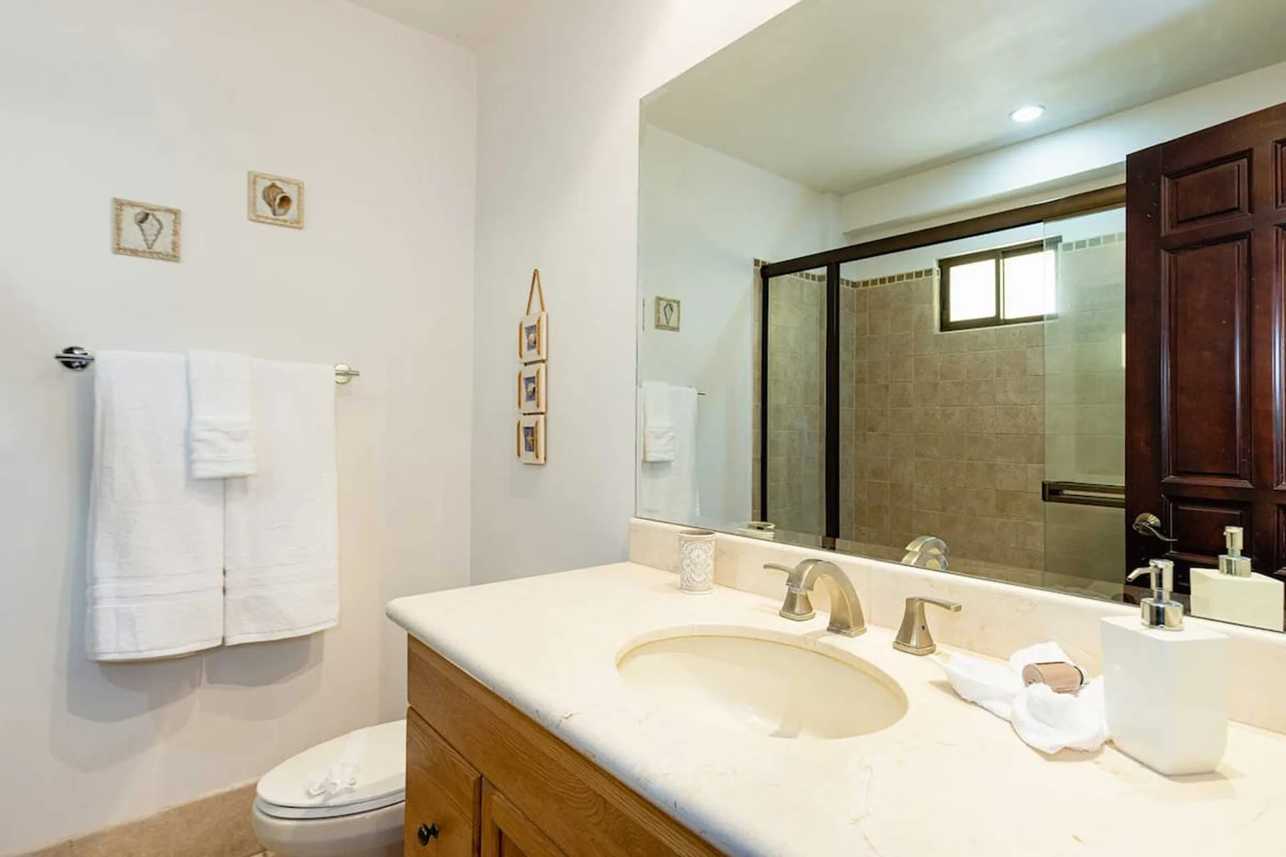 A bathroom vanity with a sink faces a large mirror and shower.