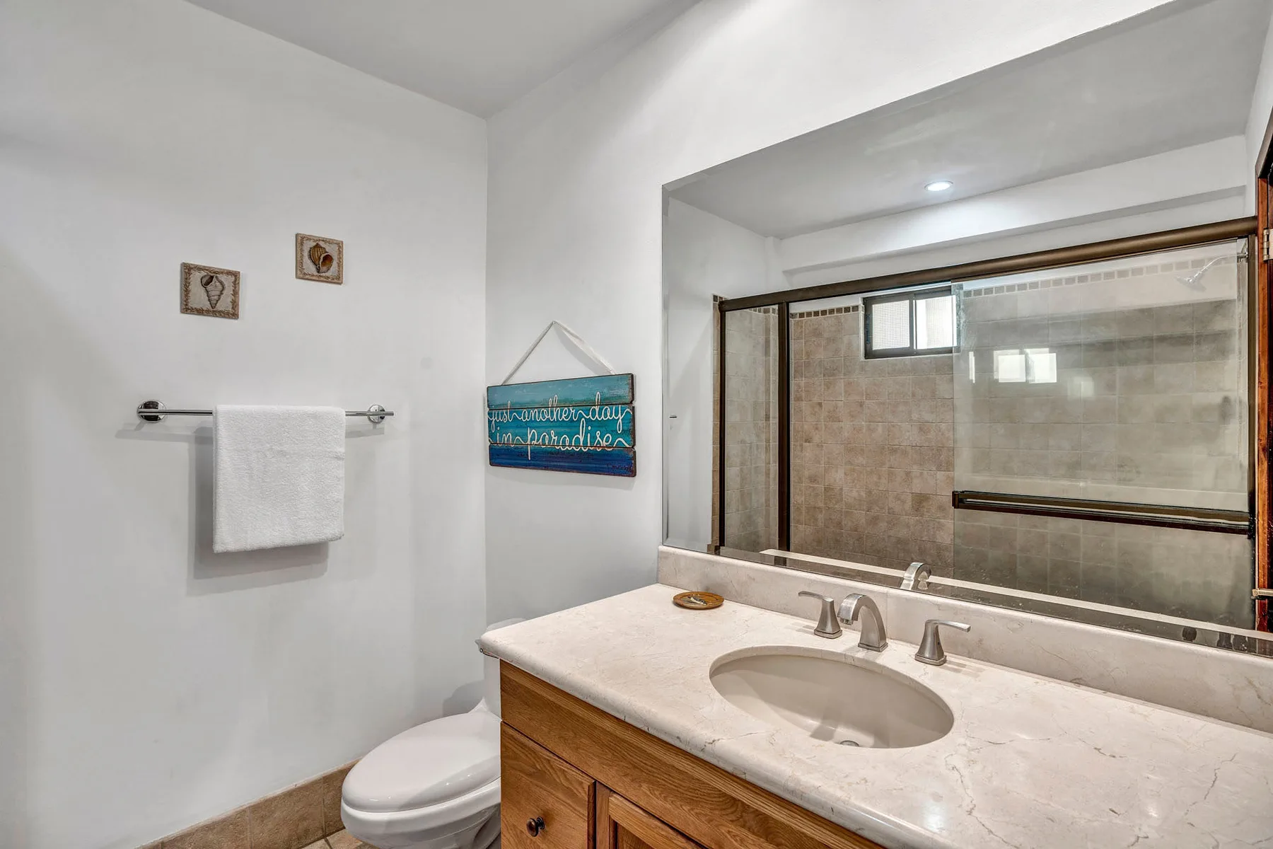 A bathroom vanity with an oval sink faces a large mirror.