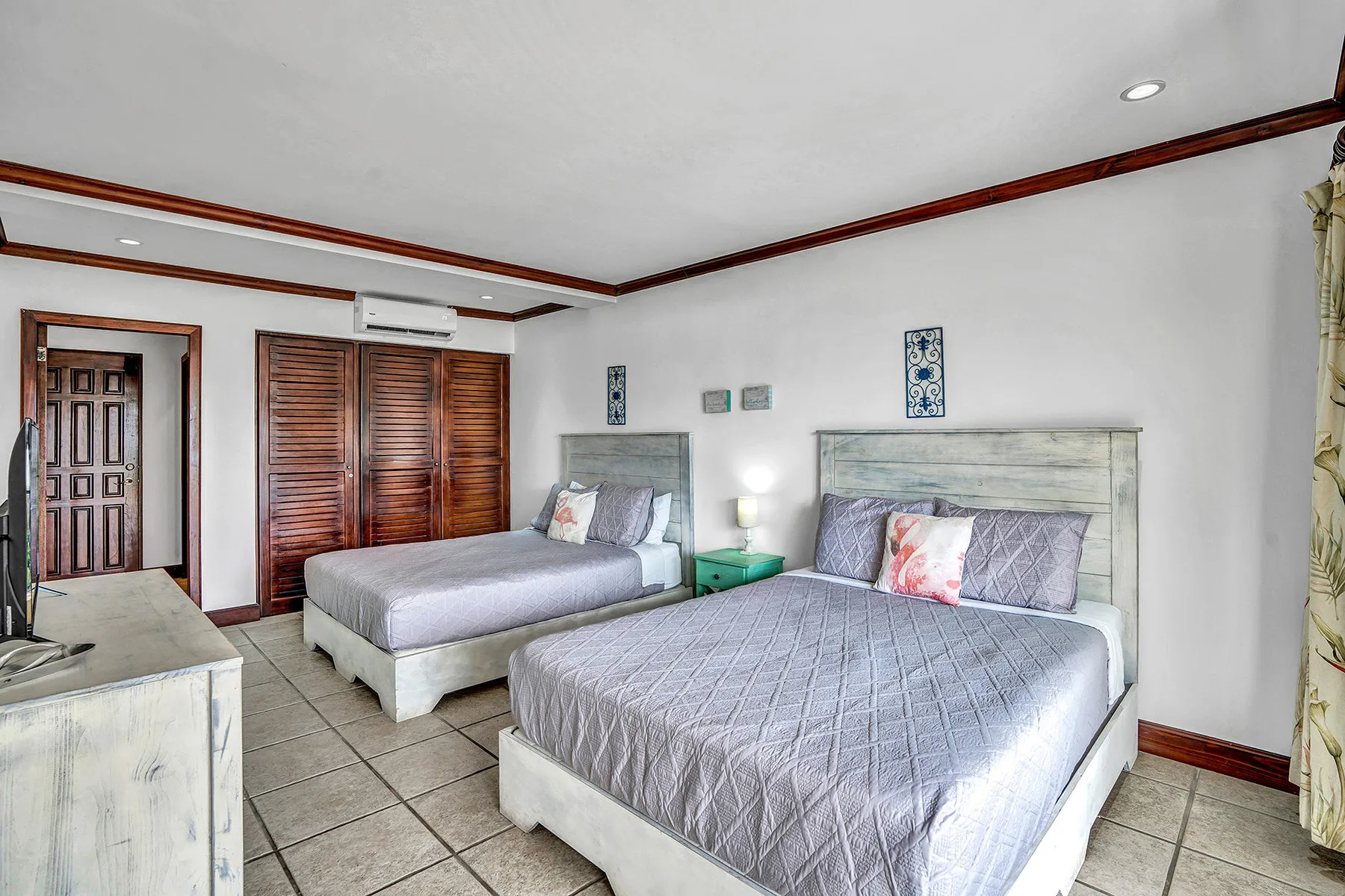 A bedroom with two beds, a bedside table, and wooden wardrobes.