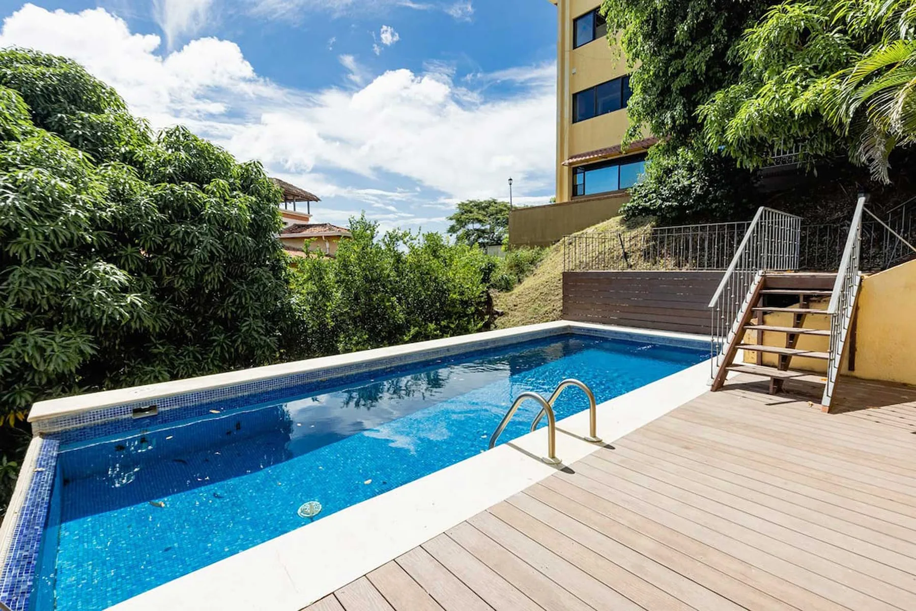 Shared amenity: An outdoor swimming pool beside a wooden deck and surrounding greenery.