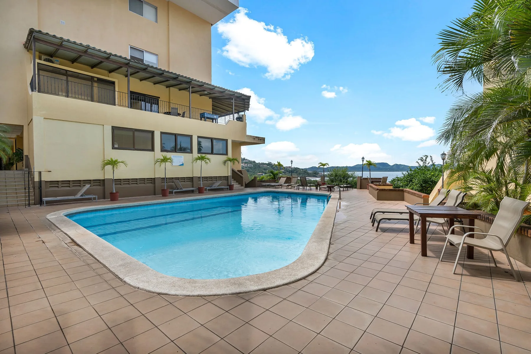 Shared amenity: An outdoor swimming pool sits beside a tiled patio with tables and seating.