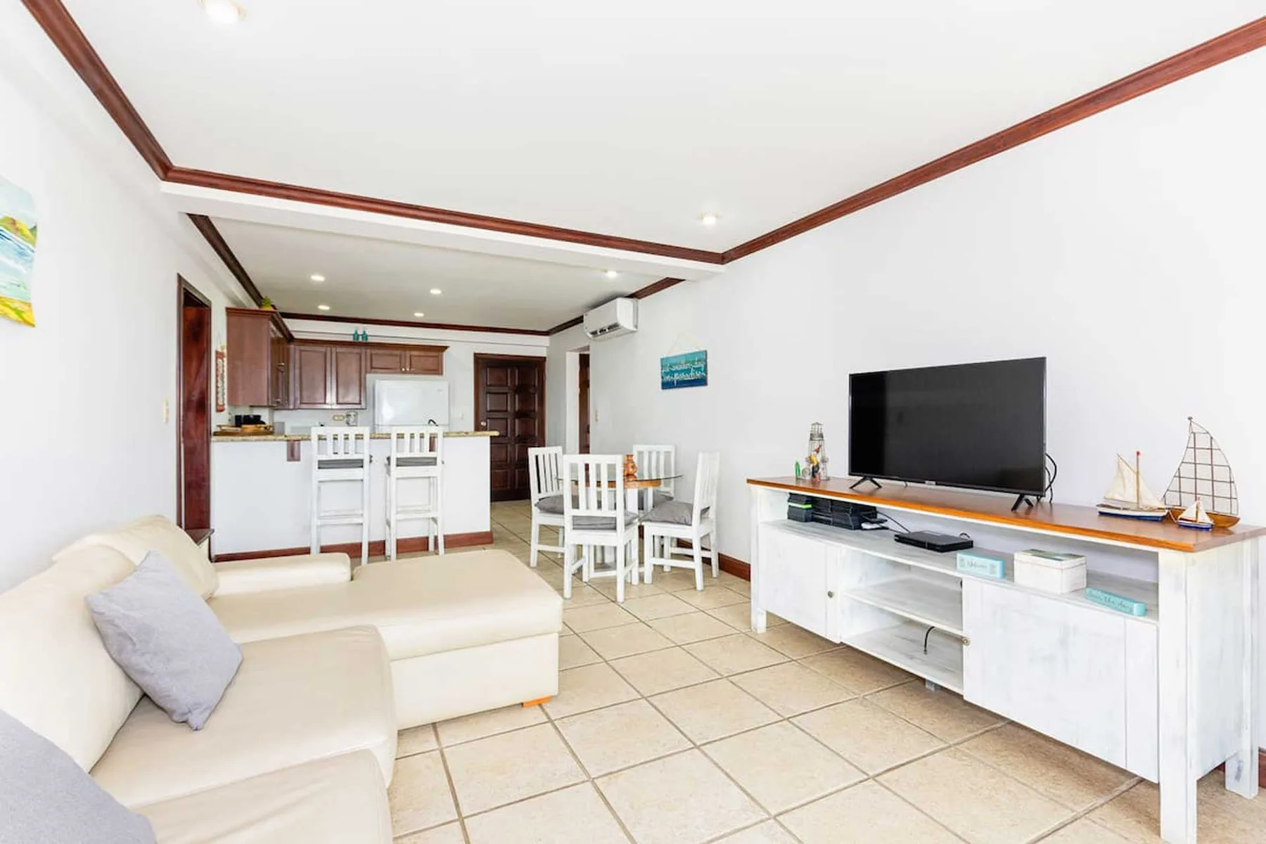 A bright open-plan living and dining area has a television and dining table.