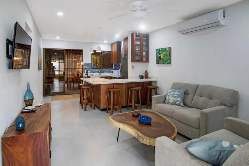 An open-plan living and dining area with a gray sofa and a kitchen island.