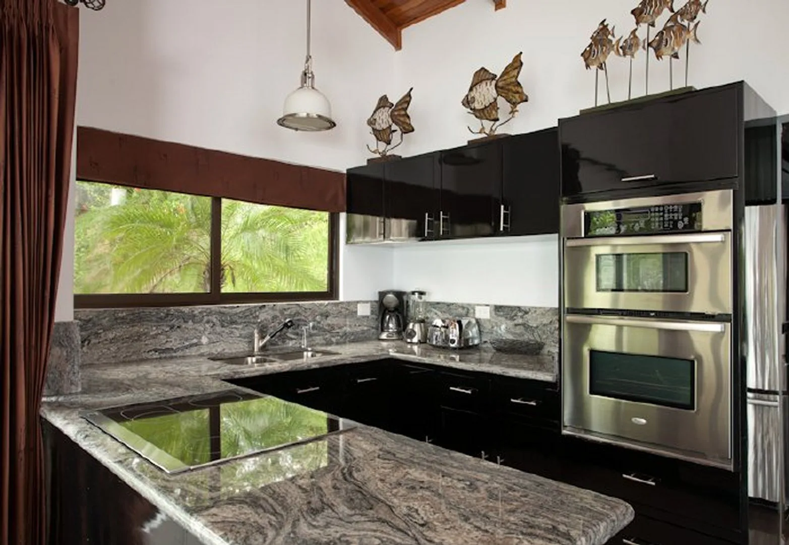 A modern kitchen with dark cabinetry and a stone countertop.