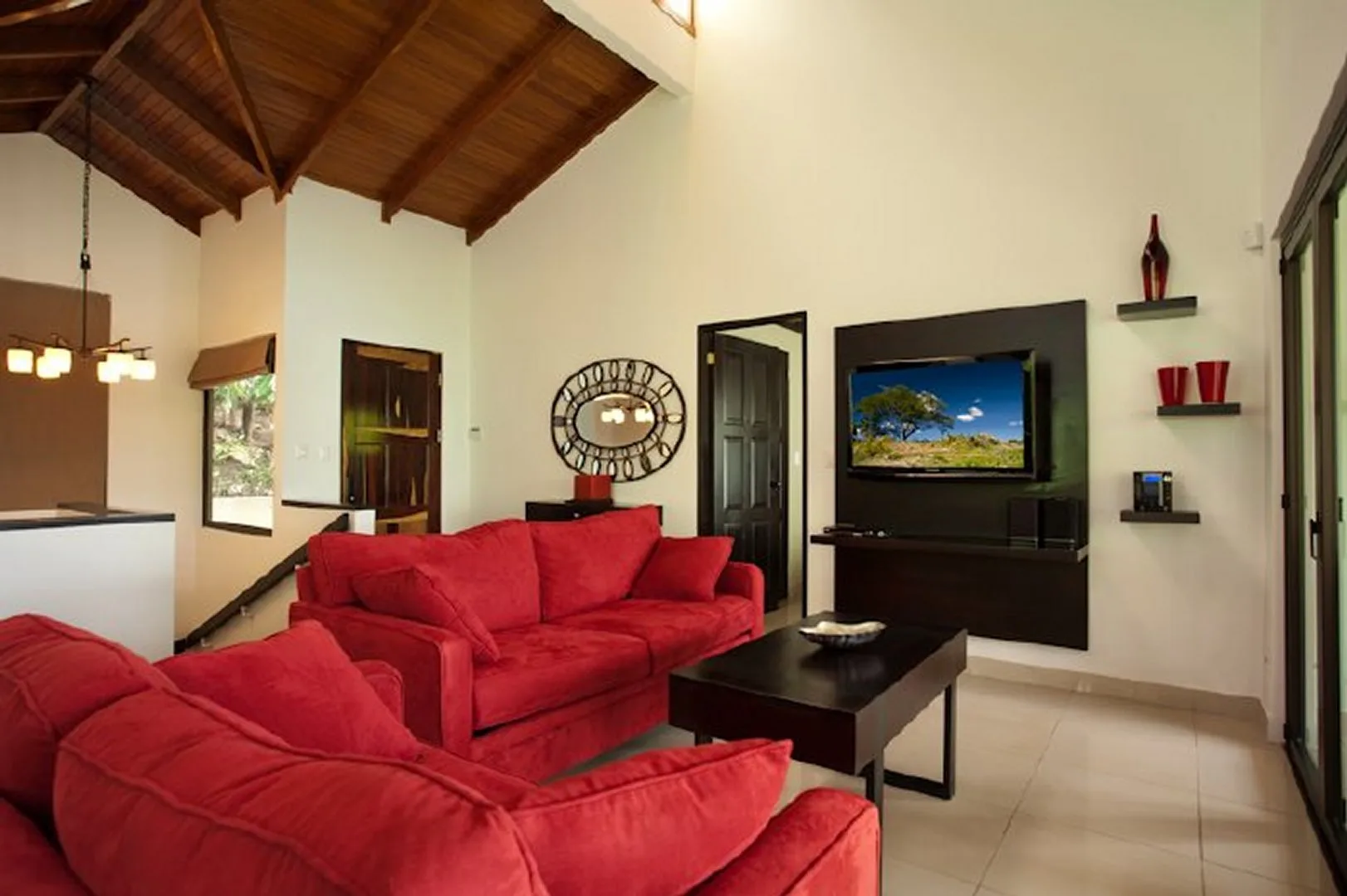 A living room with red seating, a coffee table, and a television.
