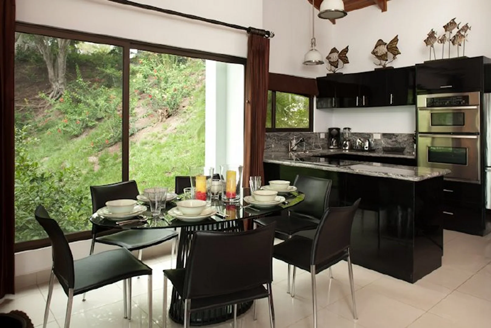 A dining area with a set table beside a modern kitchen and large windows.
