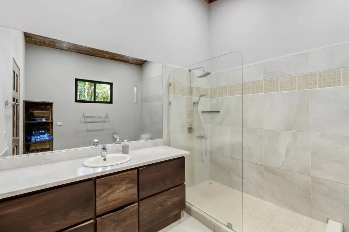 Un baño con un tocador largo y una ducha de vidrio.