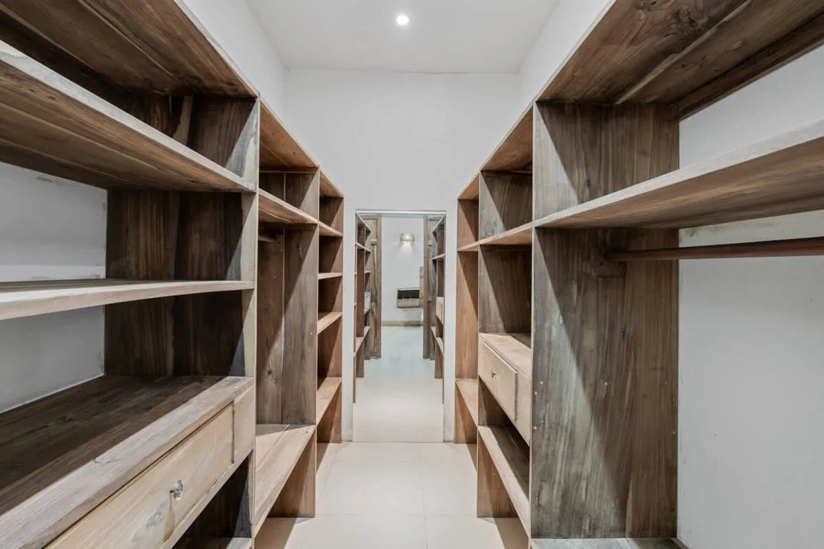 Un estrecho cuarto de almacenamiento tiene estanterías de madera a ambos lados.