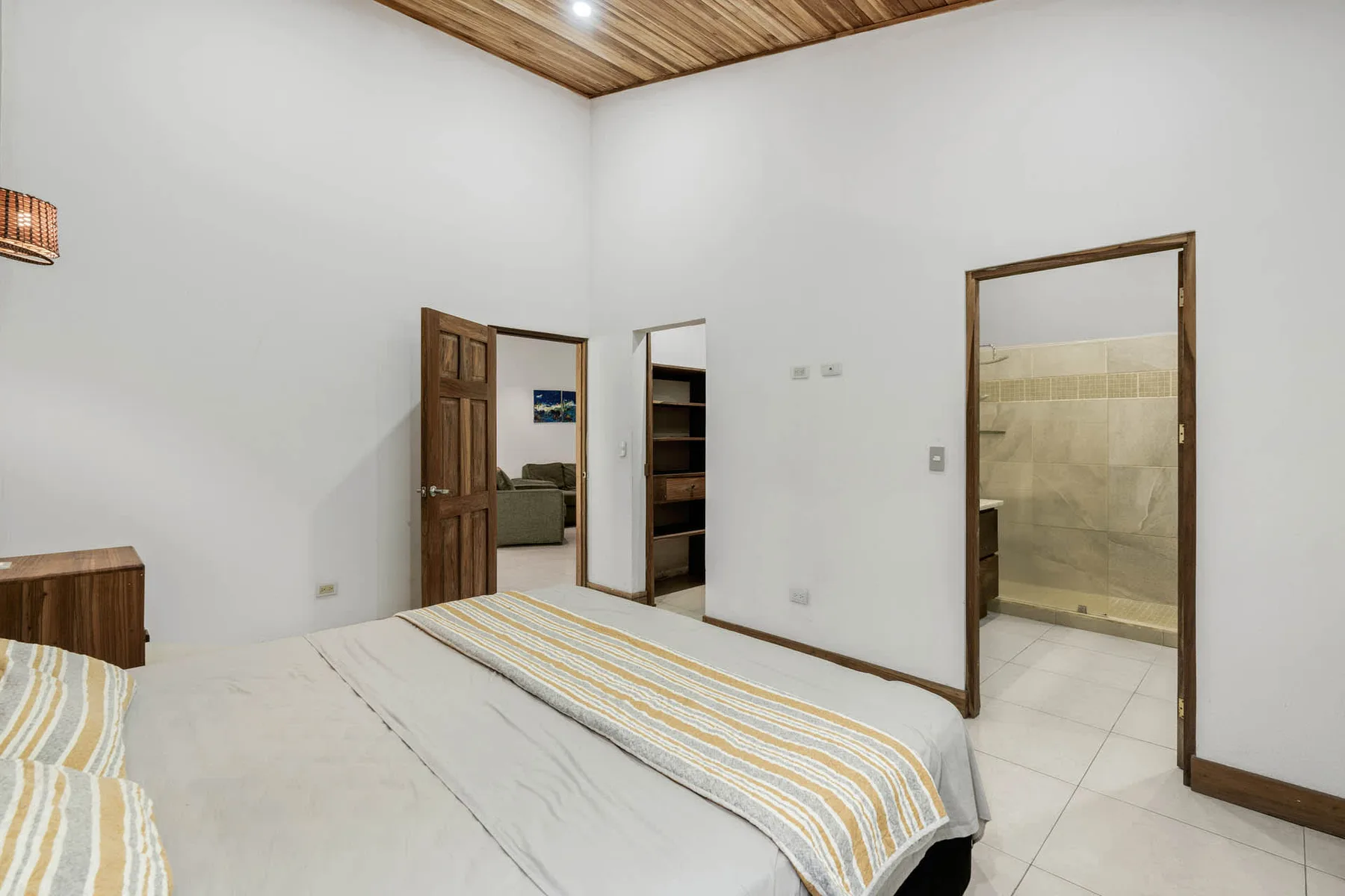 Un dormitorio con una cama y puertas abiertas que dan a habitaciones contiguas.