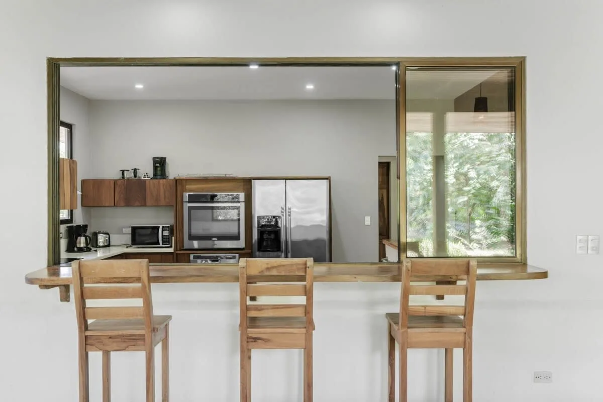 Una cocina con gabinetes de madera, electrodomésticos y una barra con asientos.
