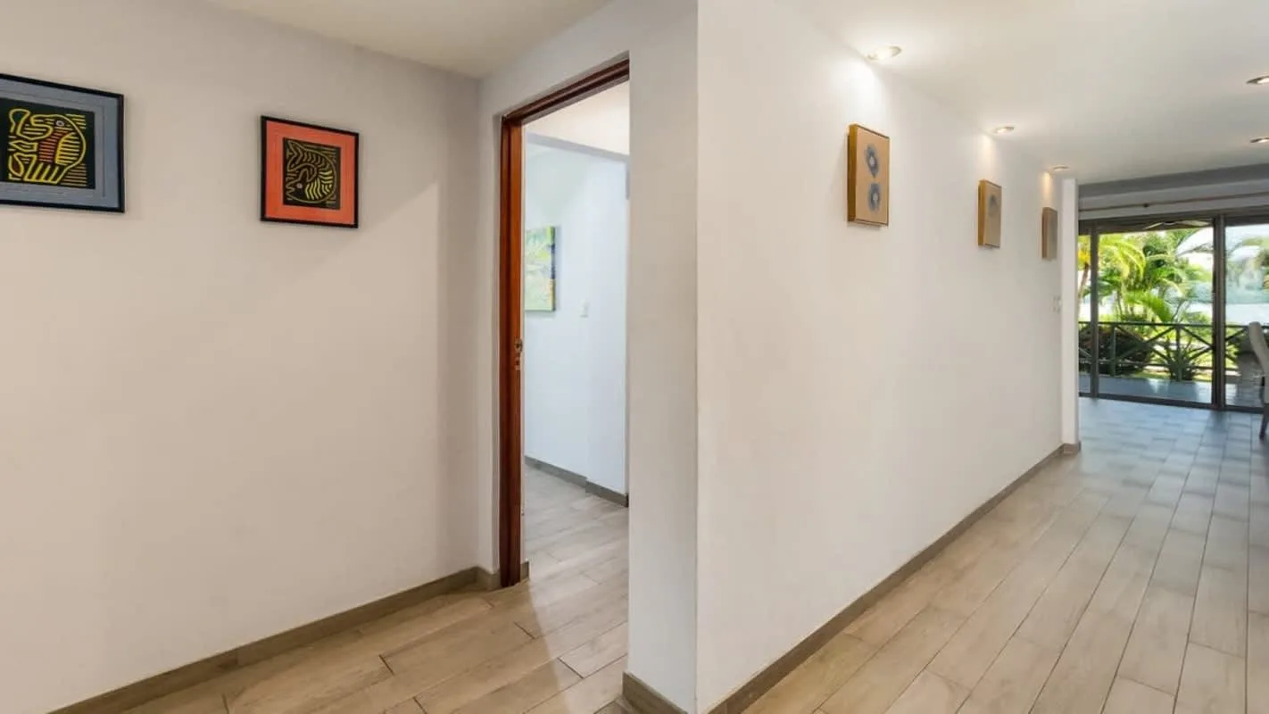 A bright hallway with framed artwork and a glass door at the far end.