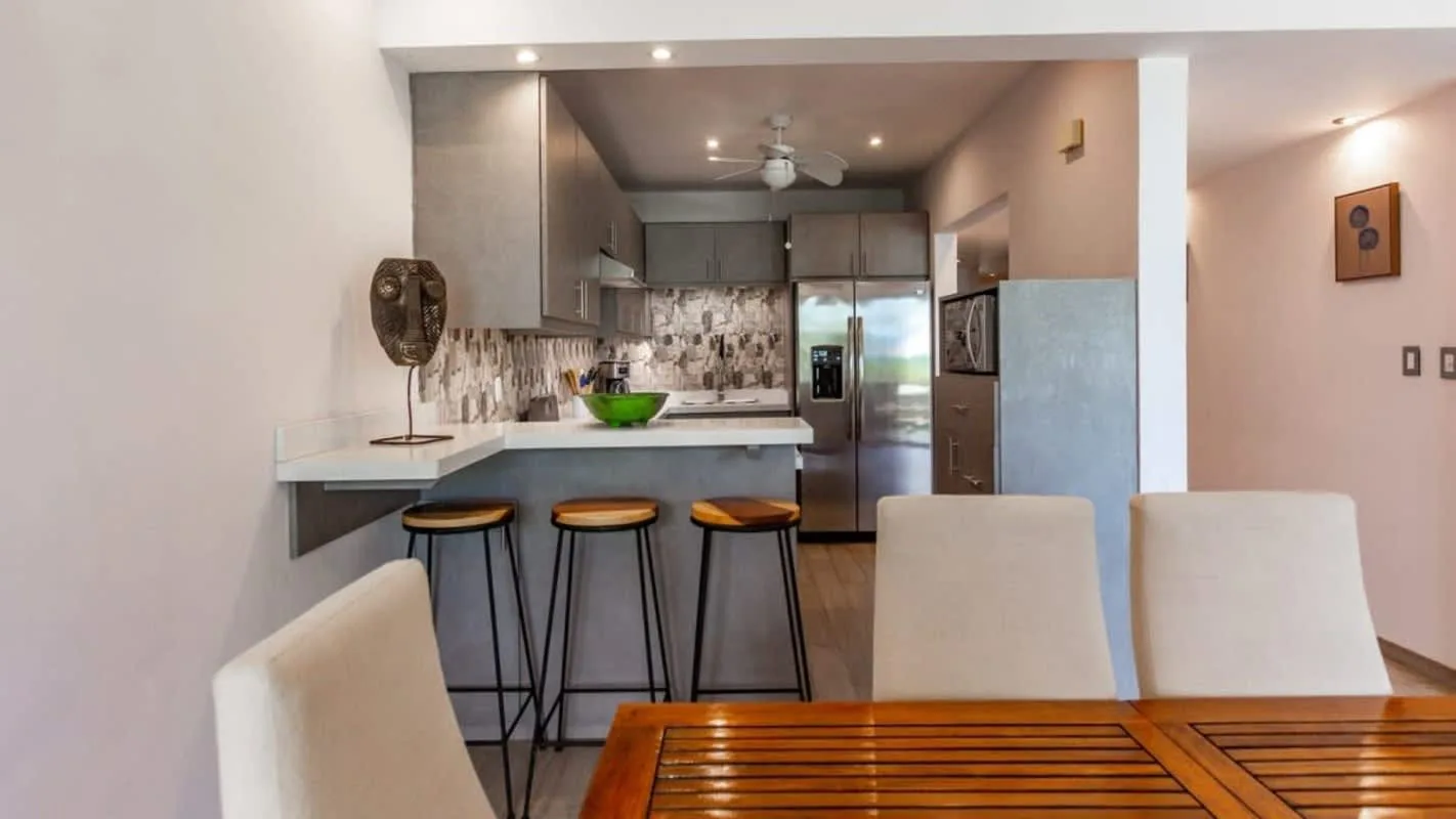 An open-plan kitchen and dining area with a wooden table and counter seating.
