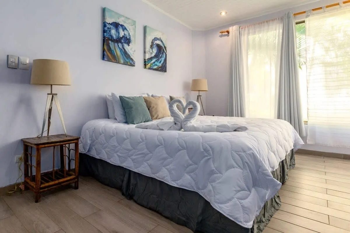 A bedroom with a neatly made bed and artwork on the wall.