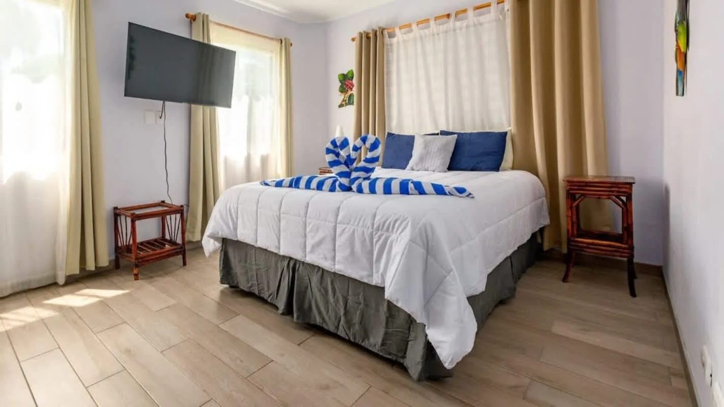 A bedroom with a neatly made bed dressed in white and blue bedding.