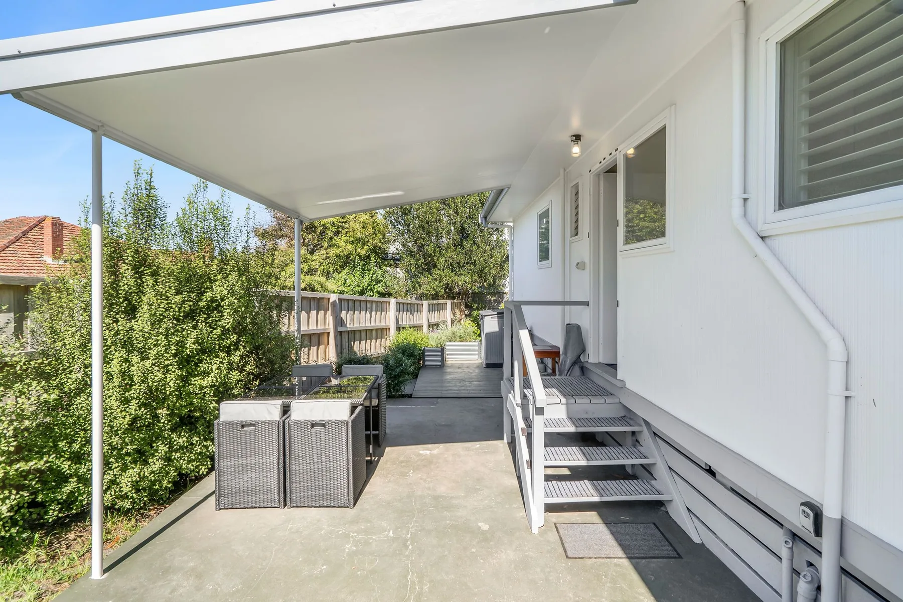A covered outdoor patio with seating beside the house.
