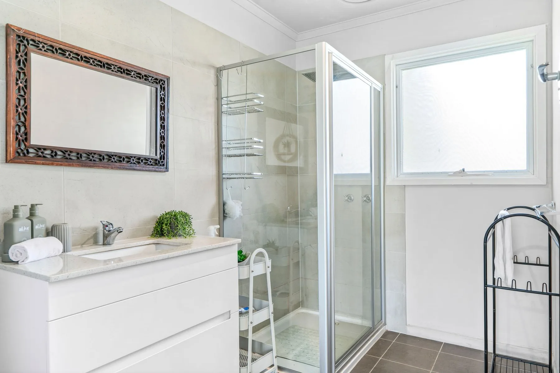 A bright bathroom with a glass shower and a vanity beneath a framed mirror.