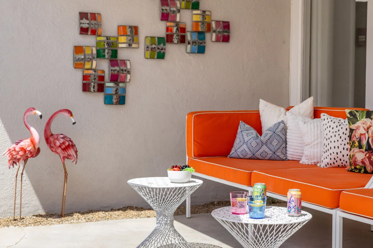 A bright lounge area with orange seating, patterned cushions, and decorative wall art.