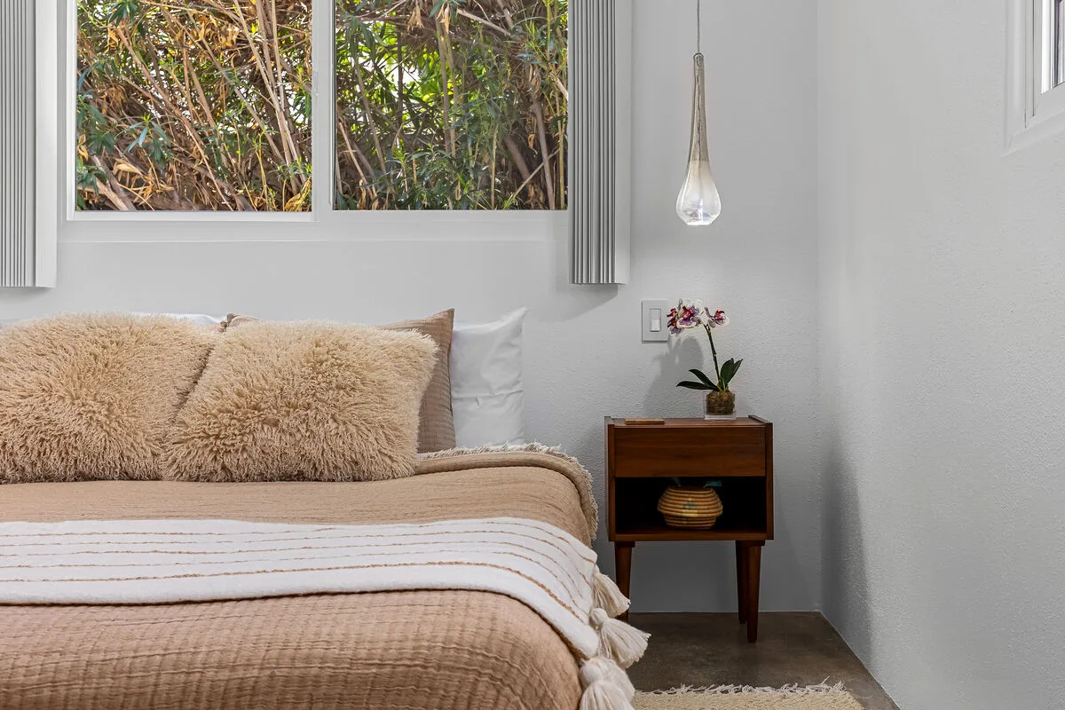 A bedroom with a bed beside a small wooden nightstand.