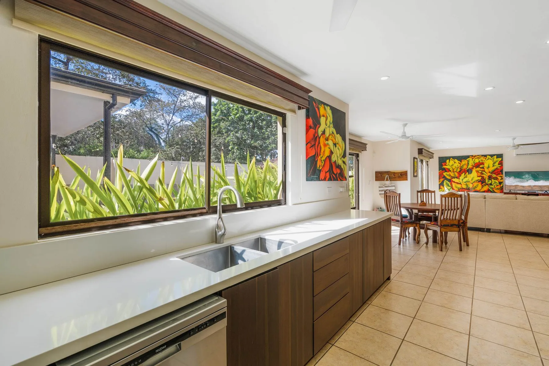 A kitchen with a long counter and sink opens onto a dining area.