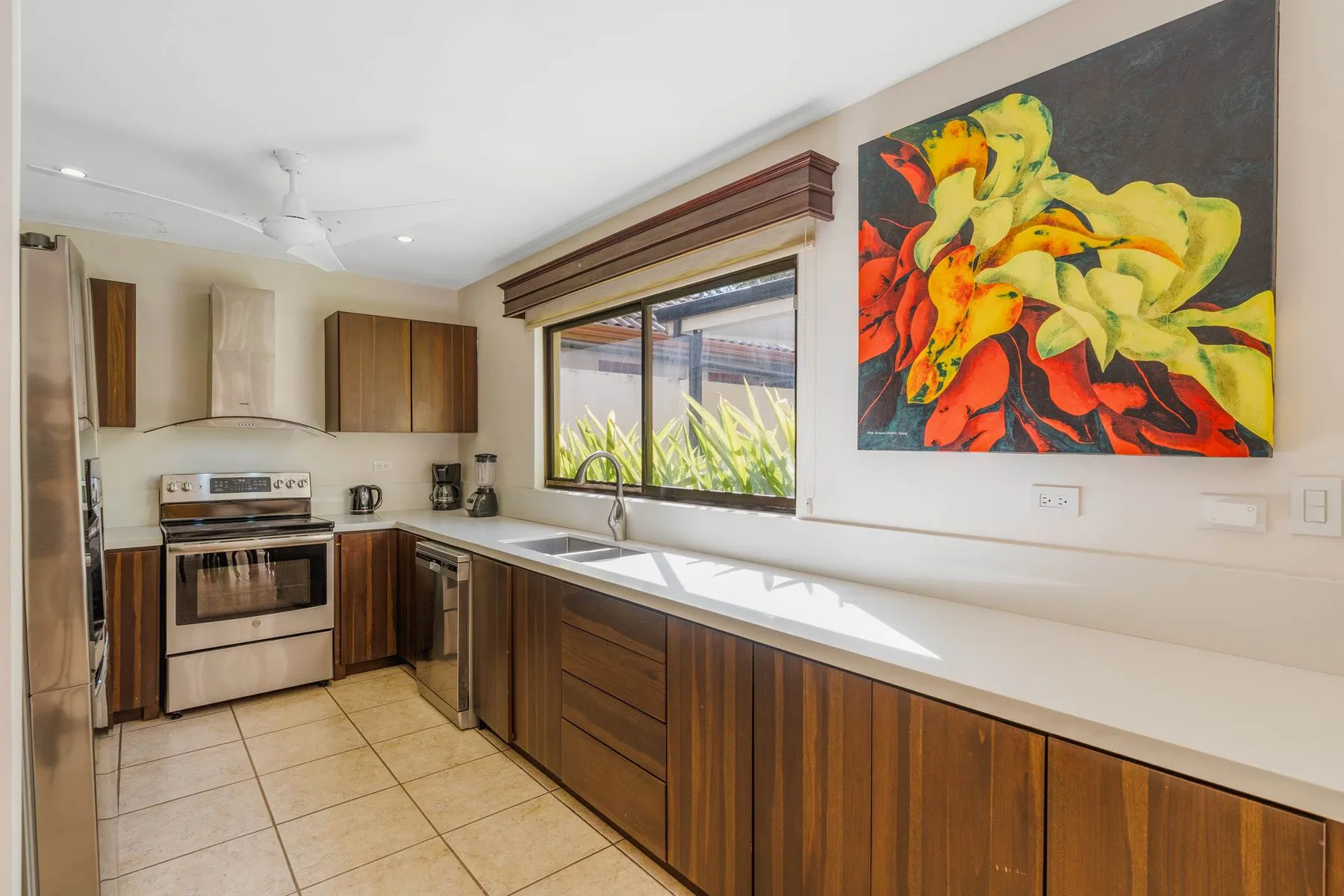 A kitchen with dark wood cabinets, a stove, and a colorful wall painting.
