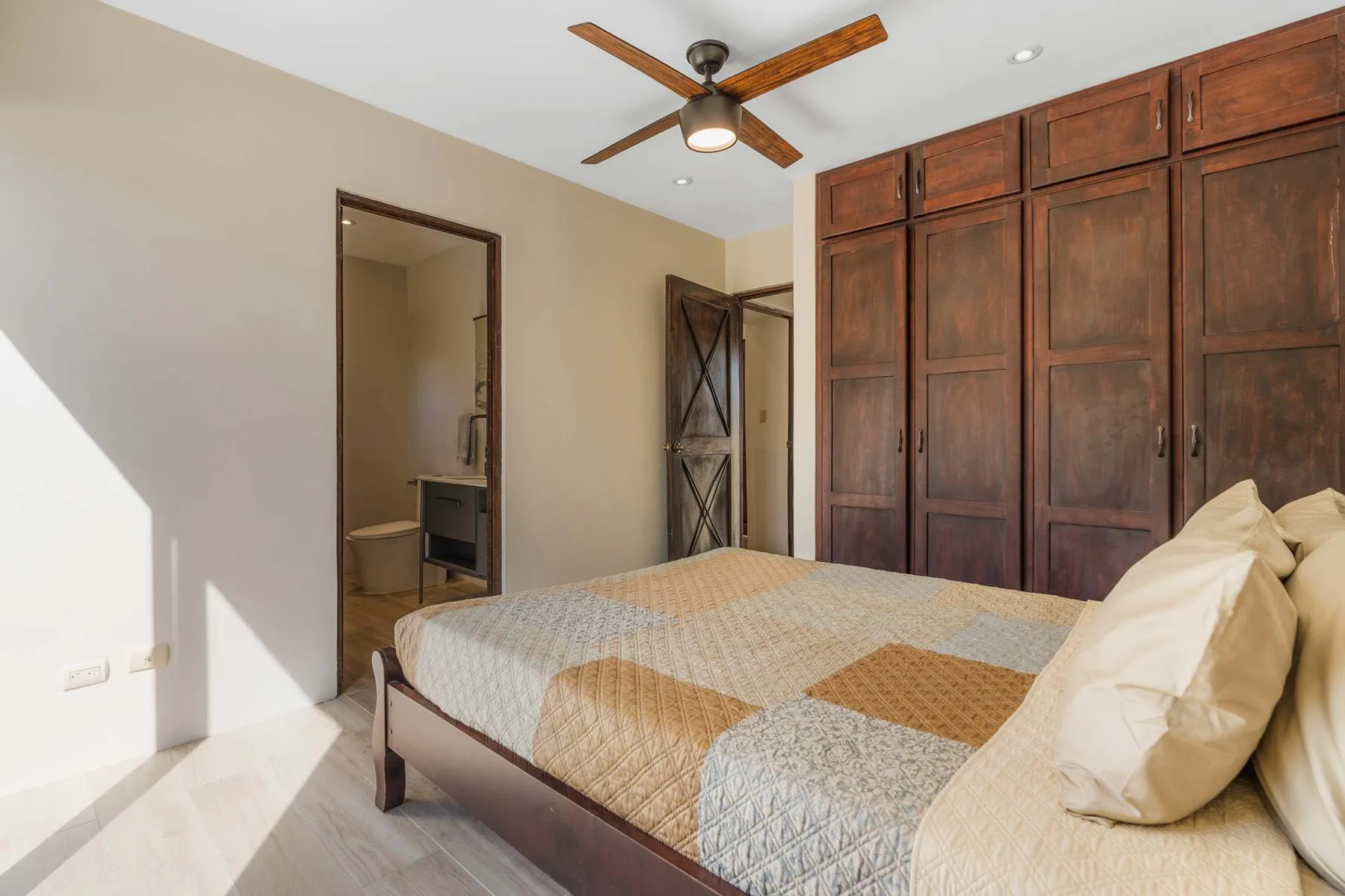 A bedroom with a bed and dark wooden wardrobes along the wall.