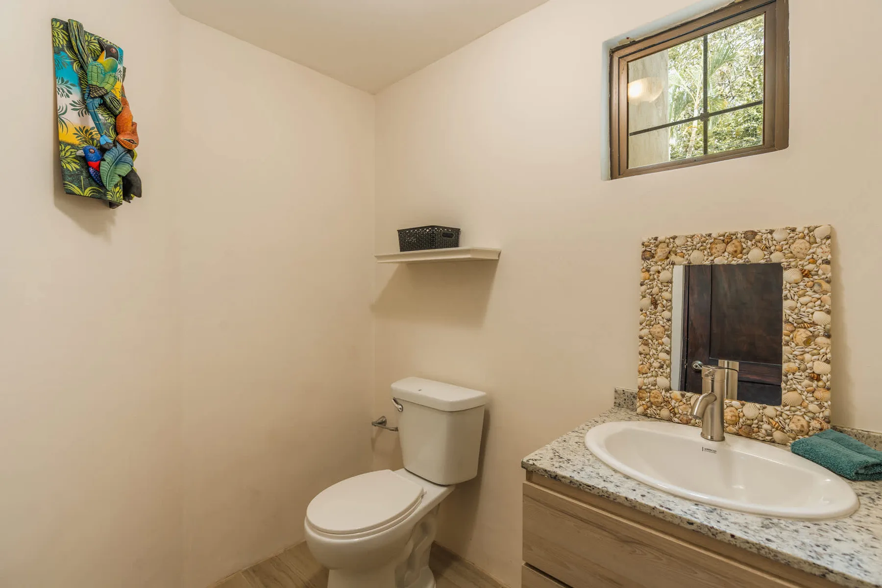 A bathroom with a toilet, sink, and small window.