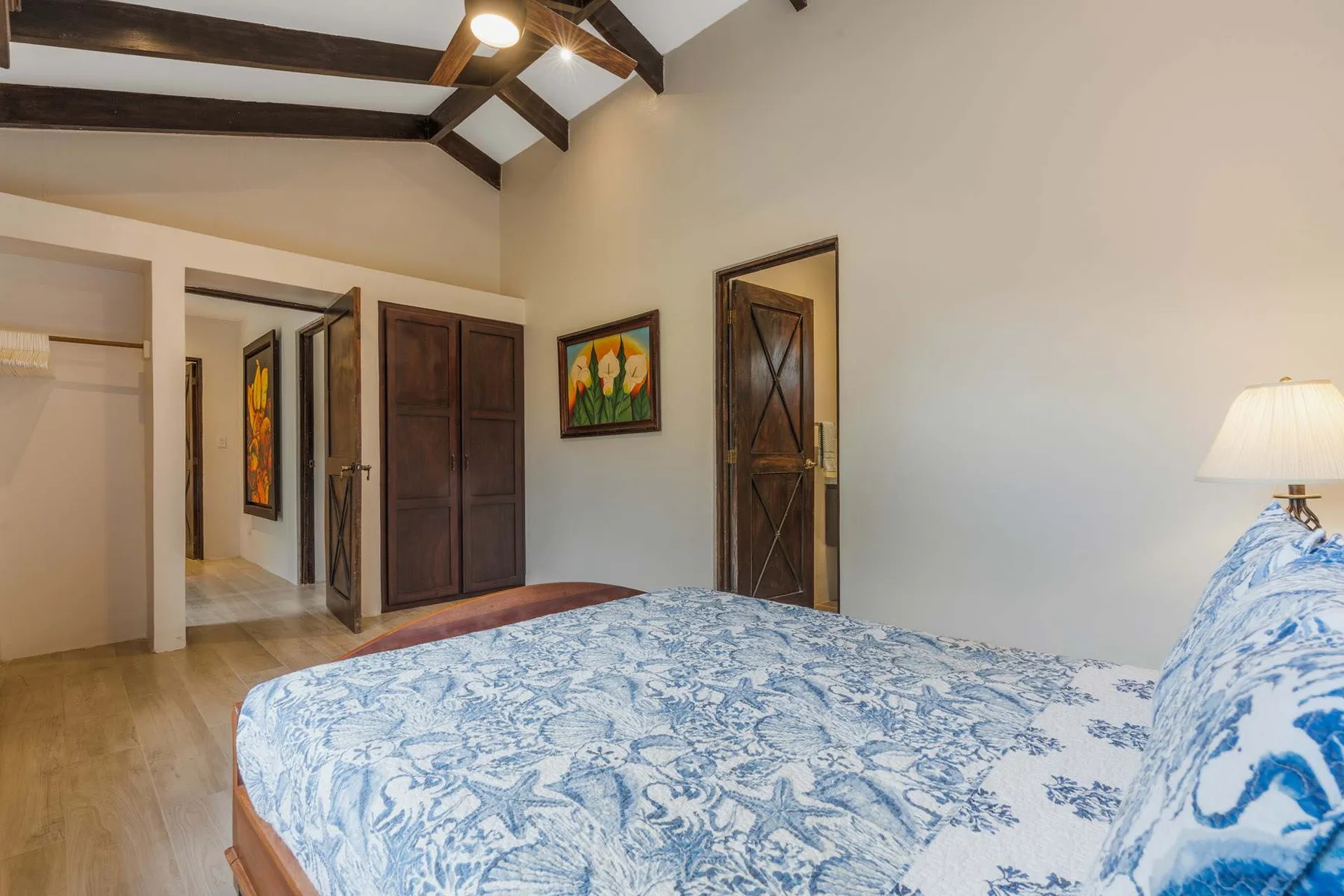A bedroom with a blue-and-white patterned bedspread and dark wooden doors.