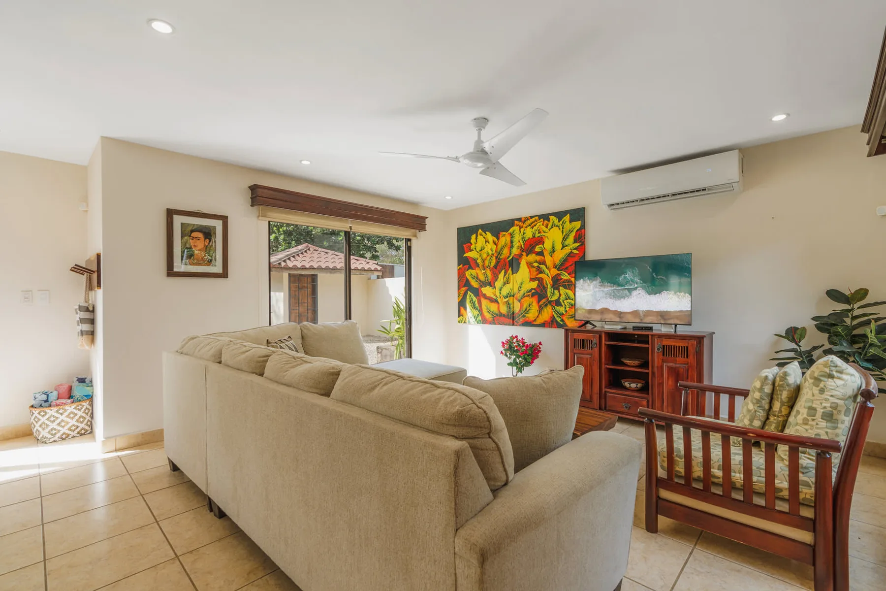 A bright living room with seating, colorful wall art, and a television.