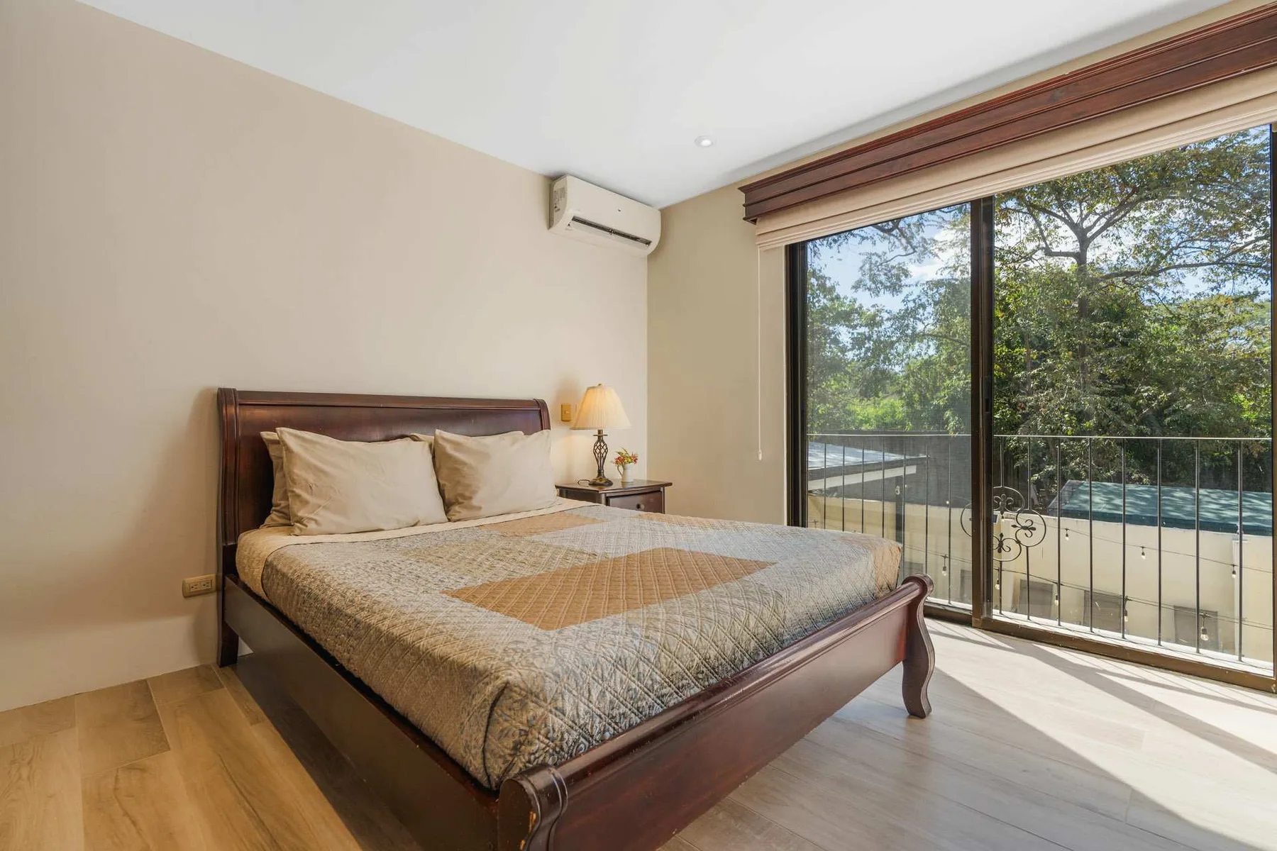 A bedroom with a large bed beside sliding glass doors opening to a balcony.