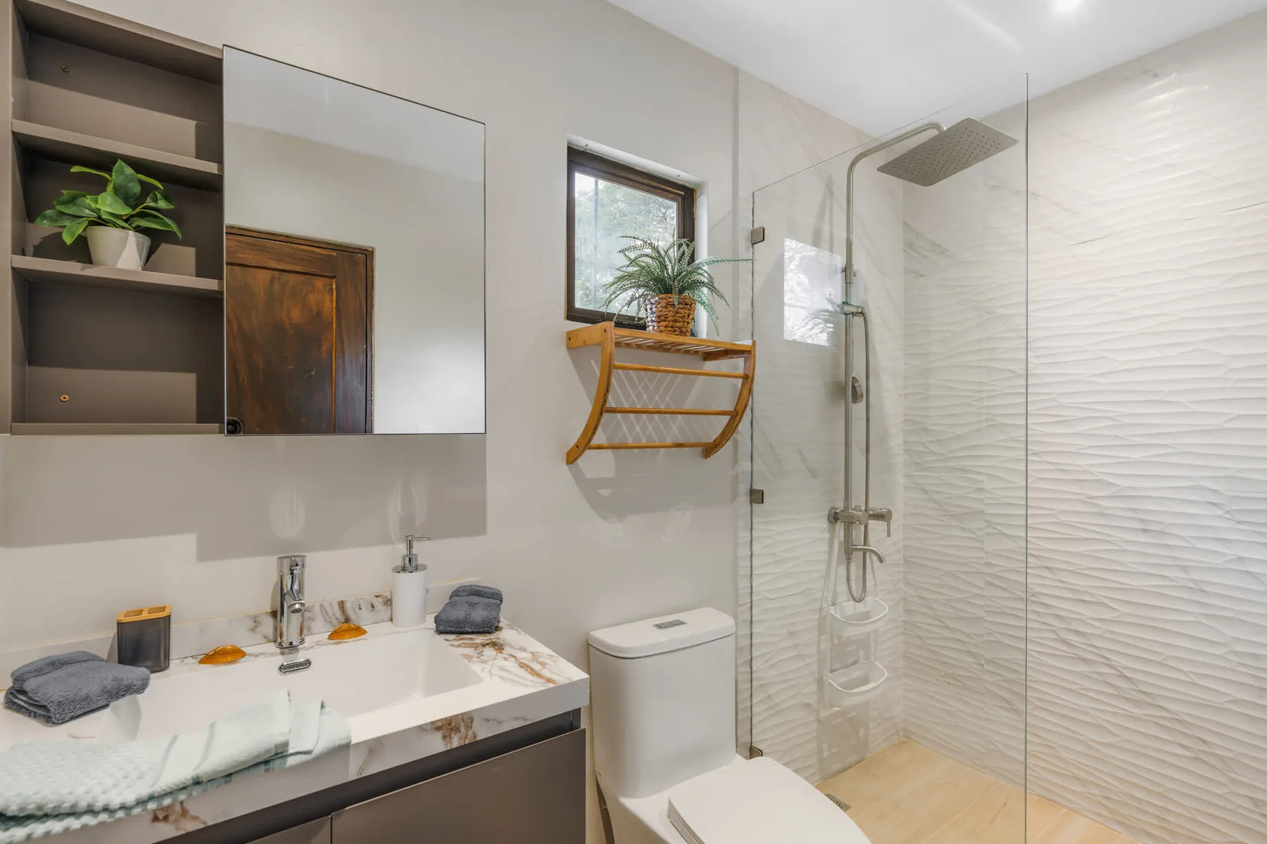 A bright bathroom with a glass shower and vanity.