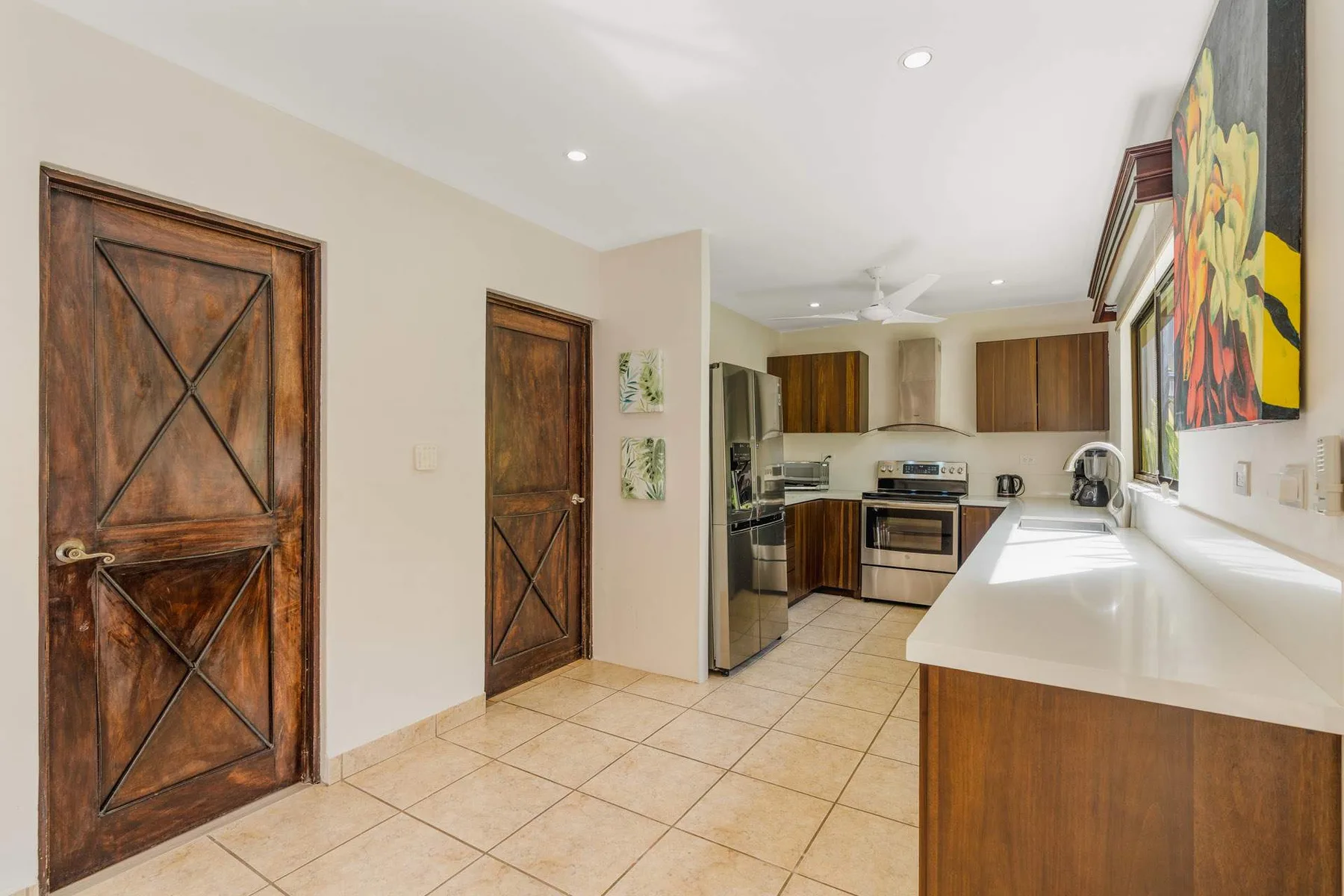 A bright kitchen with wooden cabinets, stainless steel appliances, and a long counter.