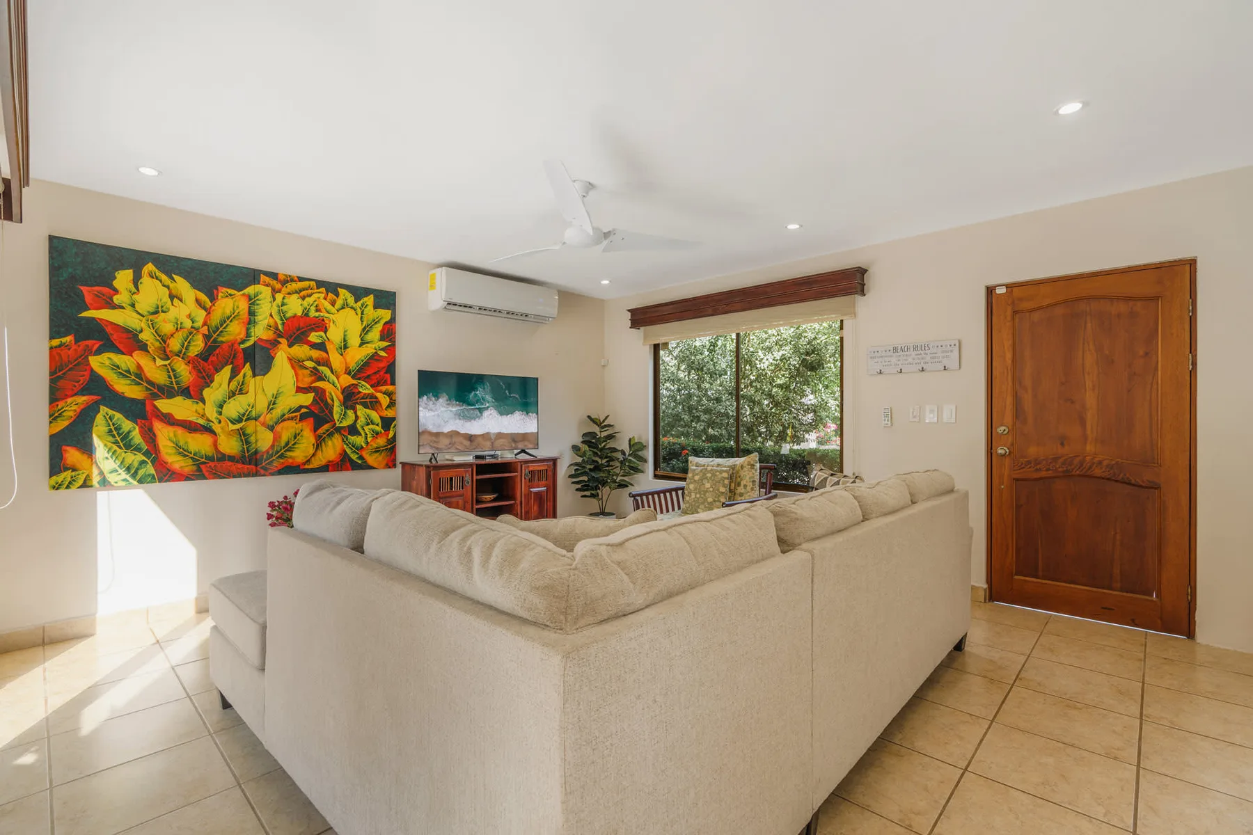 A living room with a large sectional seating area and colorful wall art.