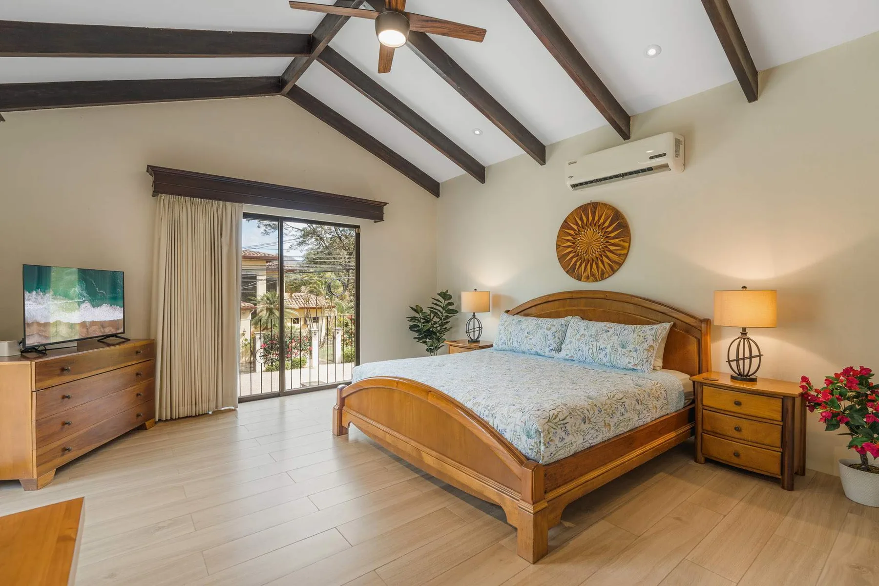 A bright bedroom with a wooden bed, bedside tables, and sliding glass doors.
