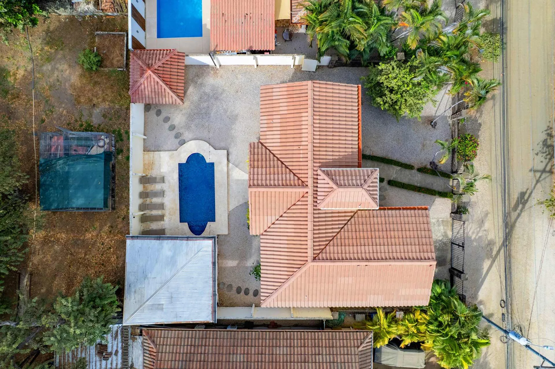 An aerial view of a tiled-roof building and a courtyard with a blue pool.