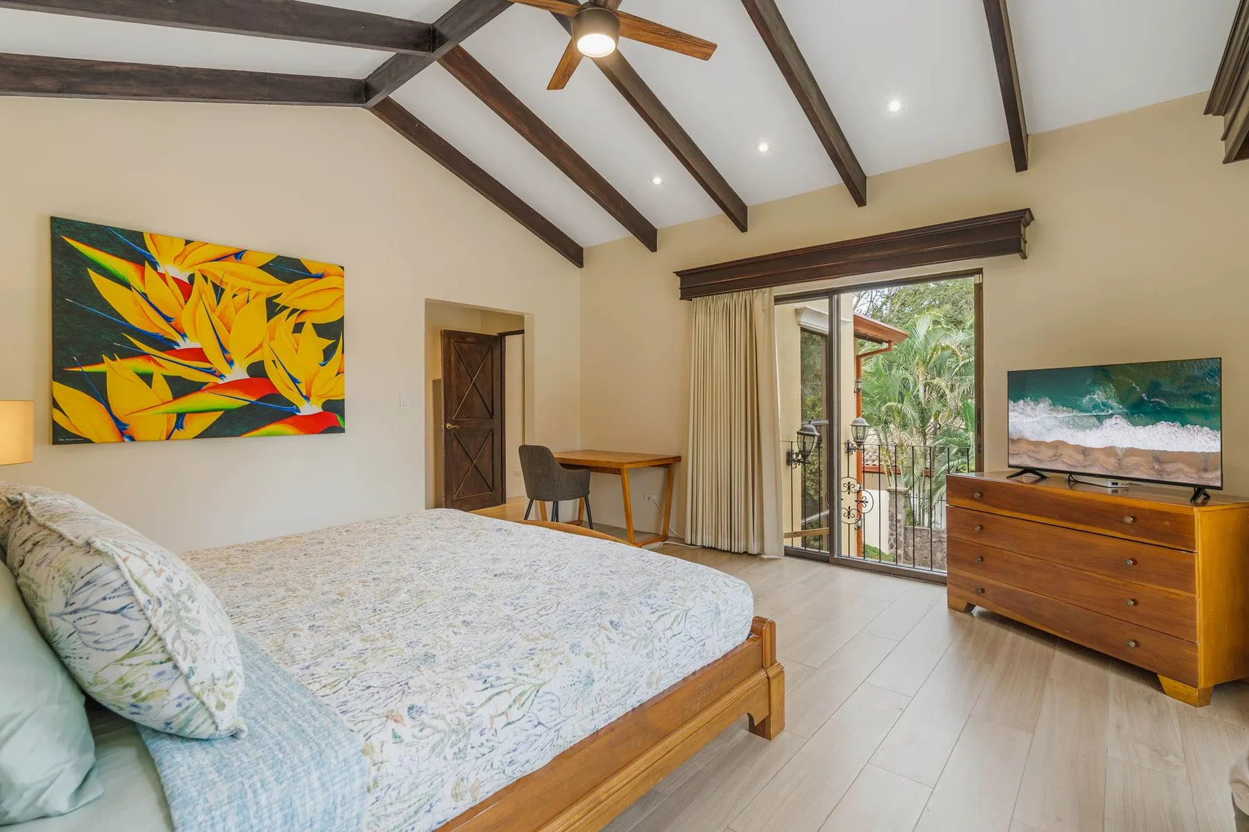 A bedroom with a bed, a desk, and glass doors opening to a garden.