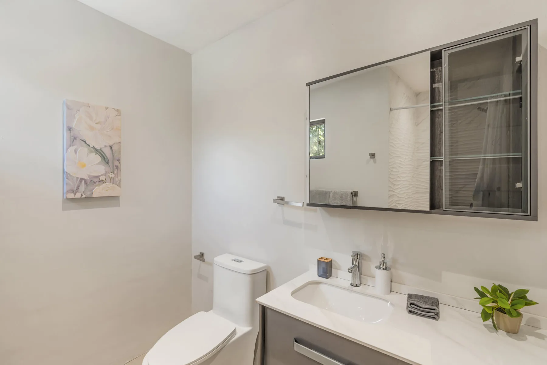 A bathroom with a toilet, sink, and large wall mirror.