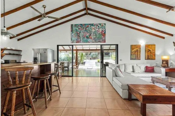 Una amplia sala-comedor cuenta con vigas de madera expuestas, una isla de cocina y un sofá seccional.