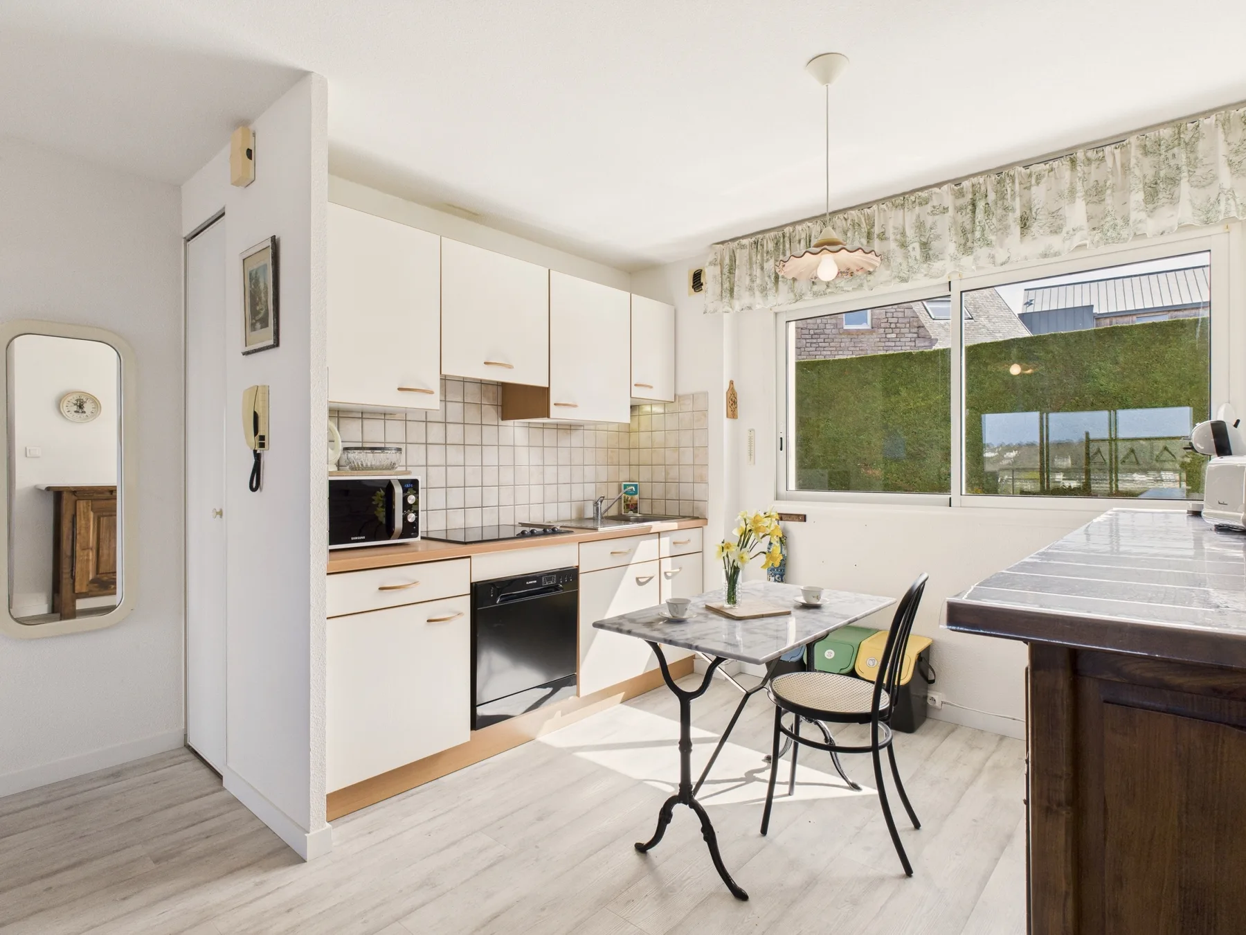 Una cocina luminosa con una zona de comedor y una mesa junto a una ventana grande.