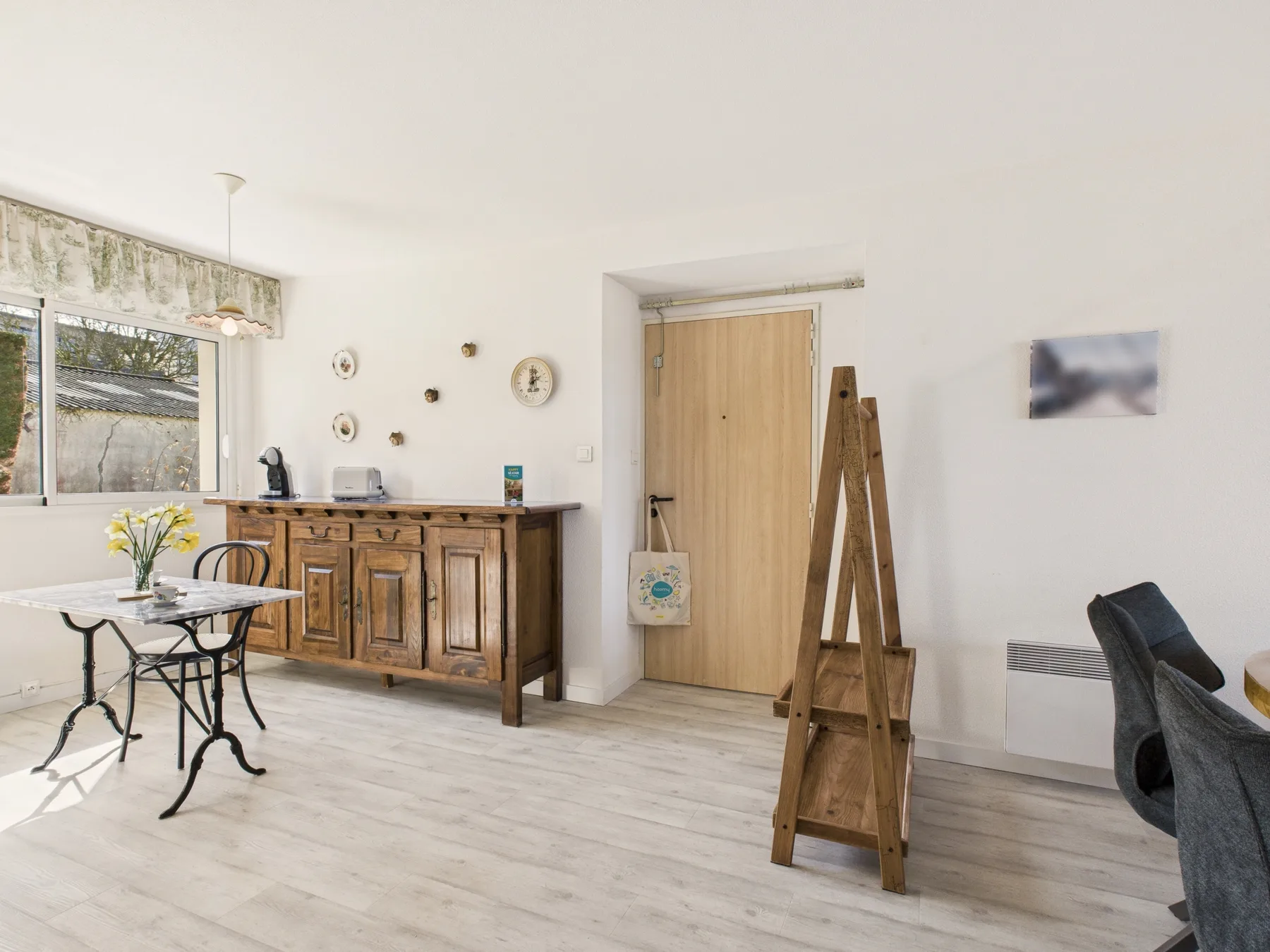 Un comedor luminoso cuenta con un aparador de madera y una mesa pequeña junto a la ventana.